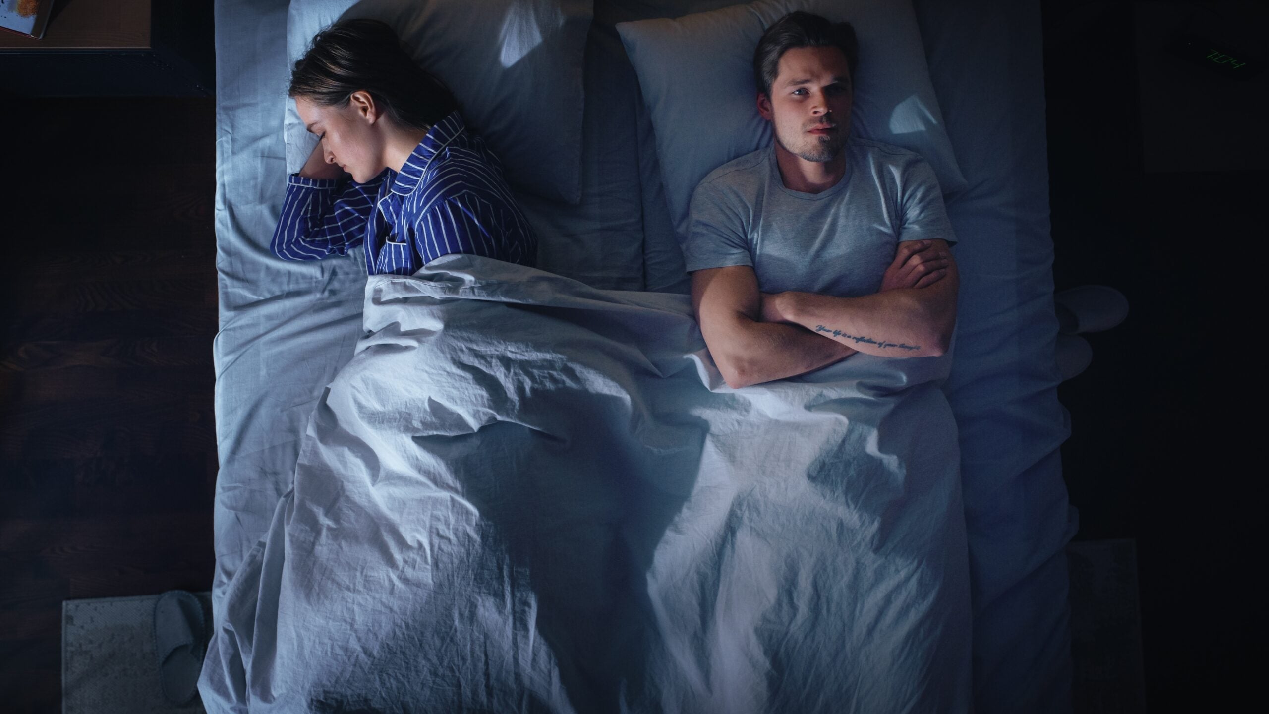 A very unhappy married couple in bed.