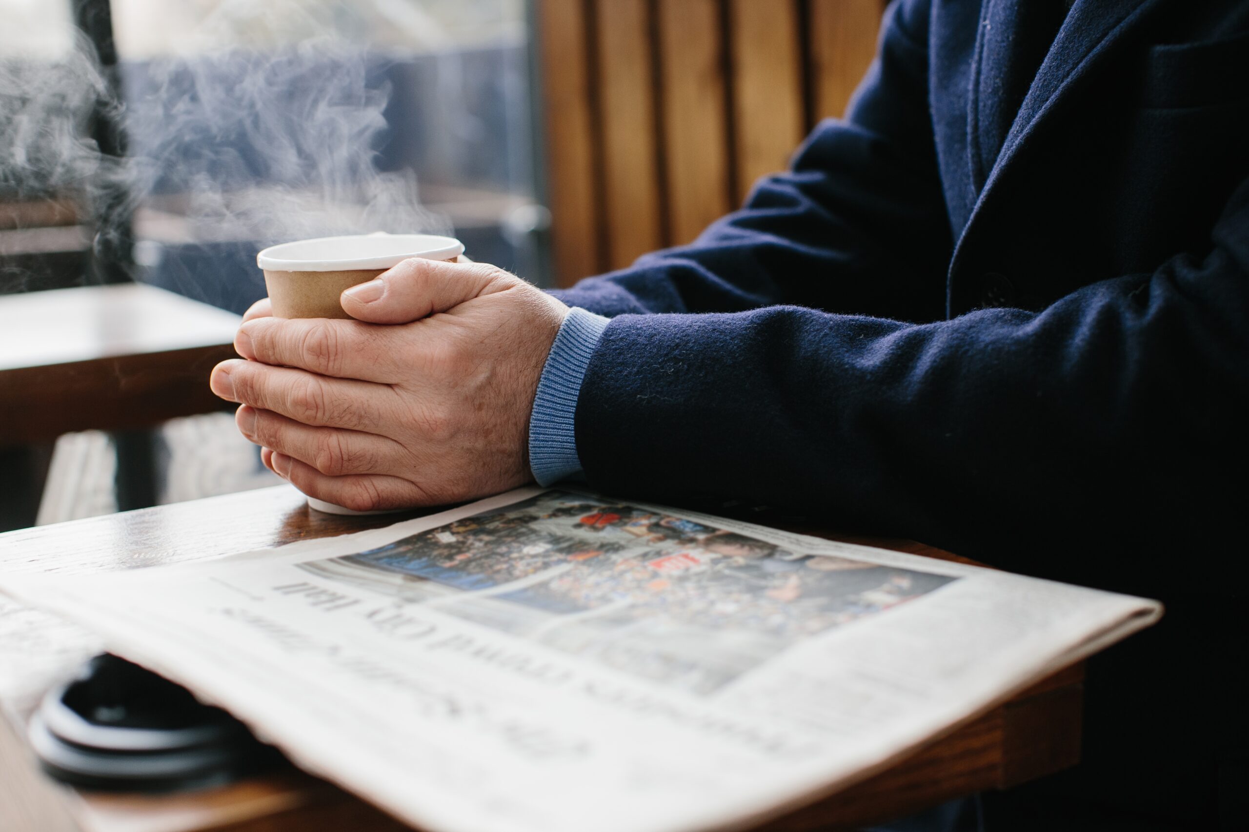 A senior man reading the paper in a cafe.