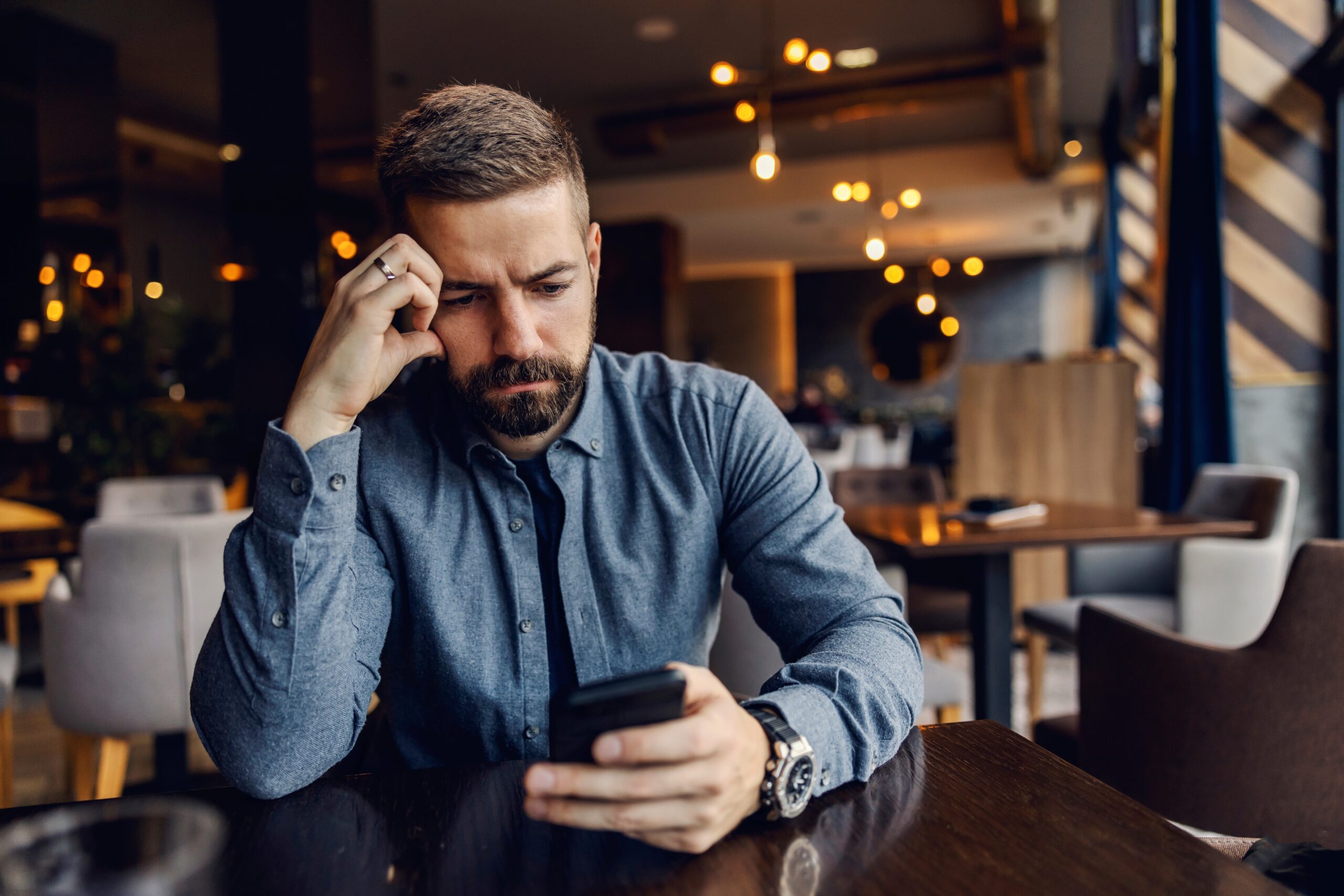 An anxious man on his phone at a cafe.