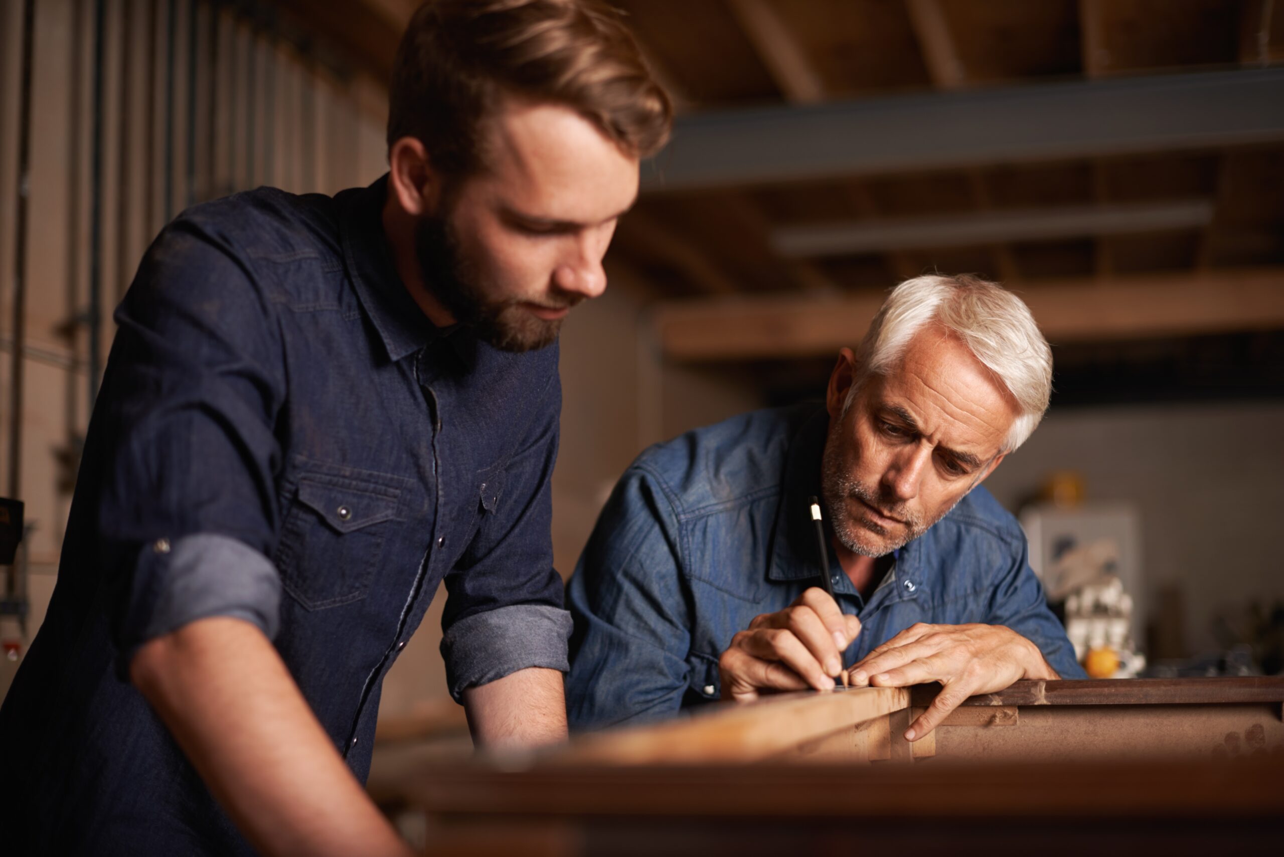 A father and his adult son working in a word shop together.