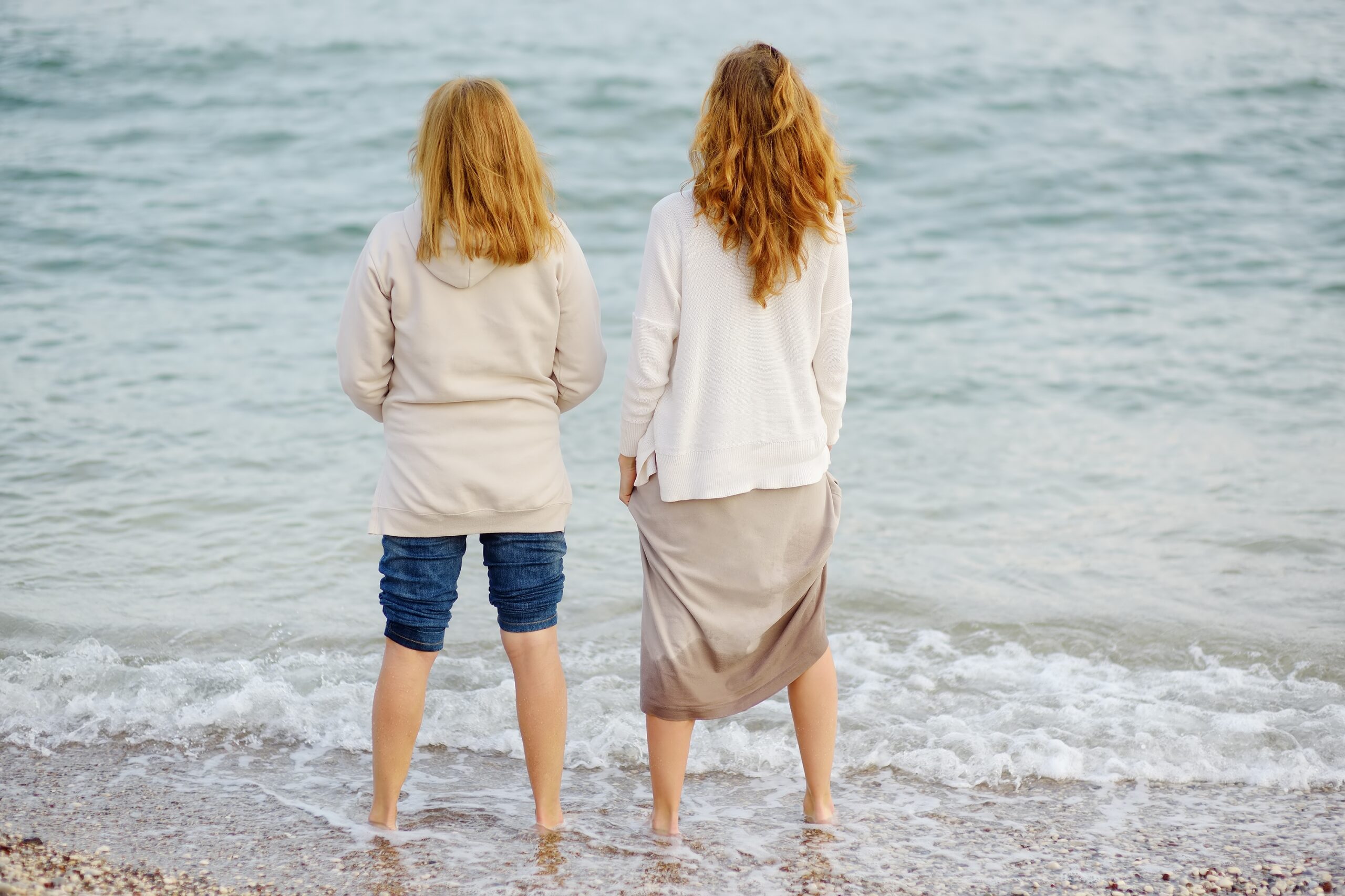 A mother and her adult daughter on a walk at the sea.