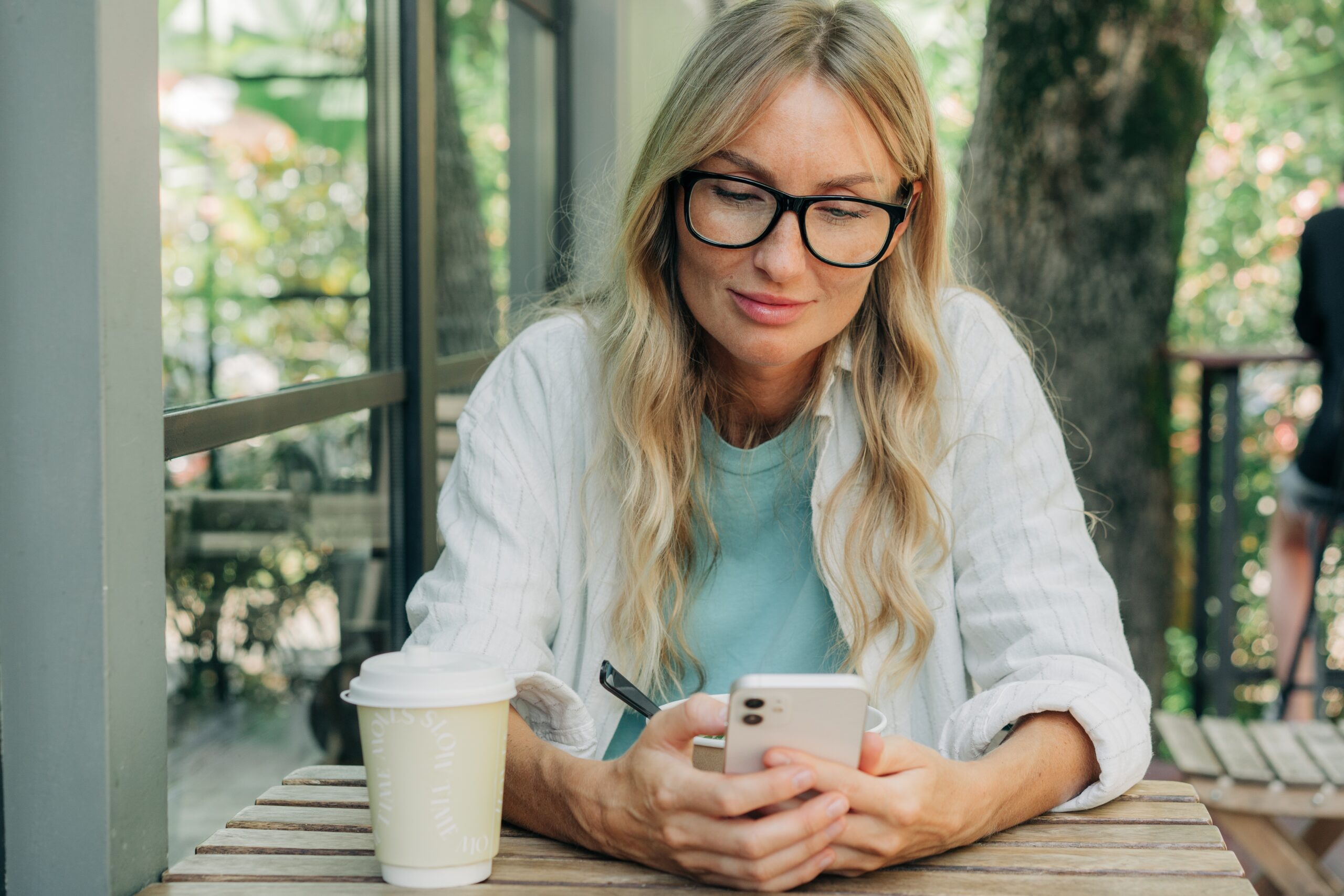 A middle aged woman having coffee in a cafe.