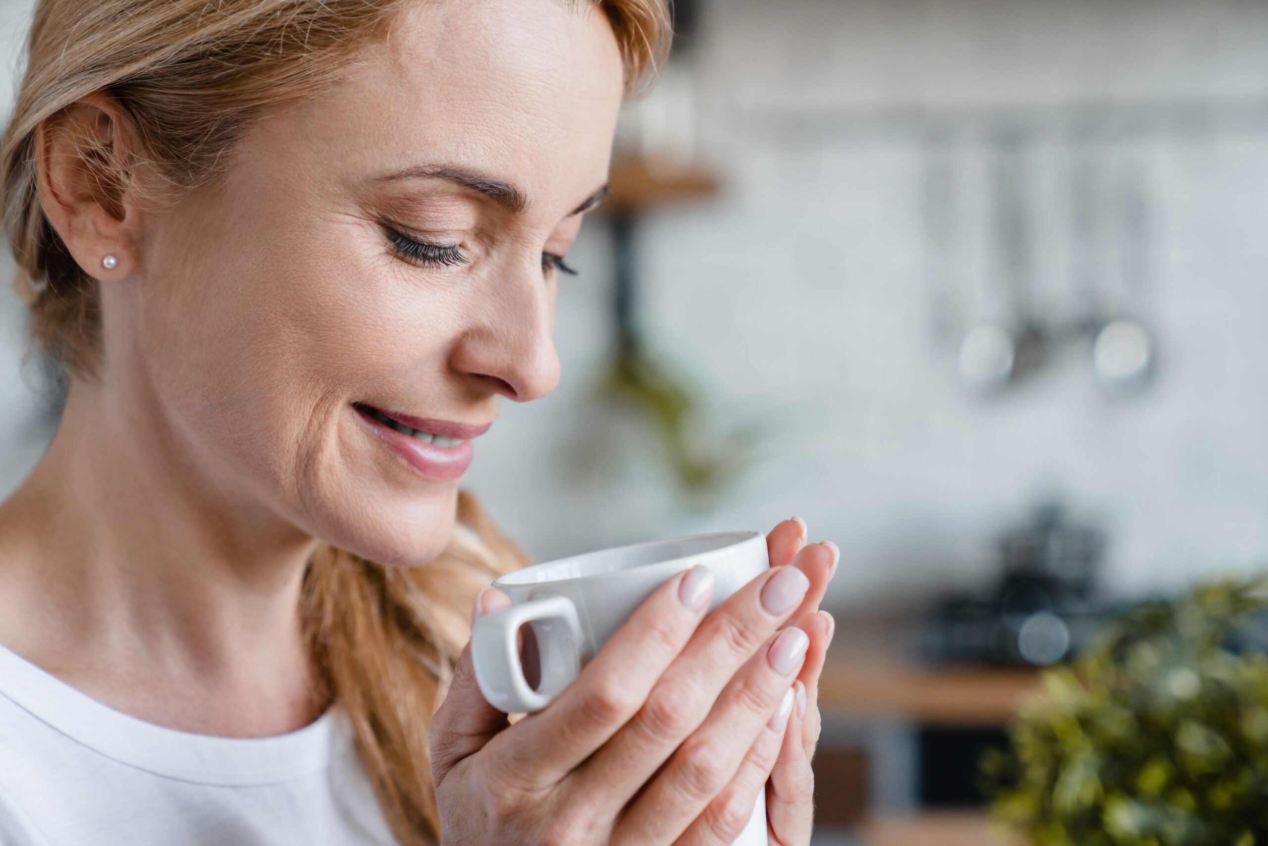 A middle aged woman enjoying her morning coffee.