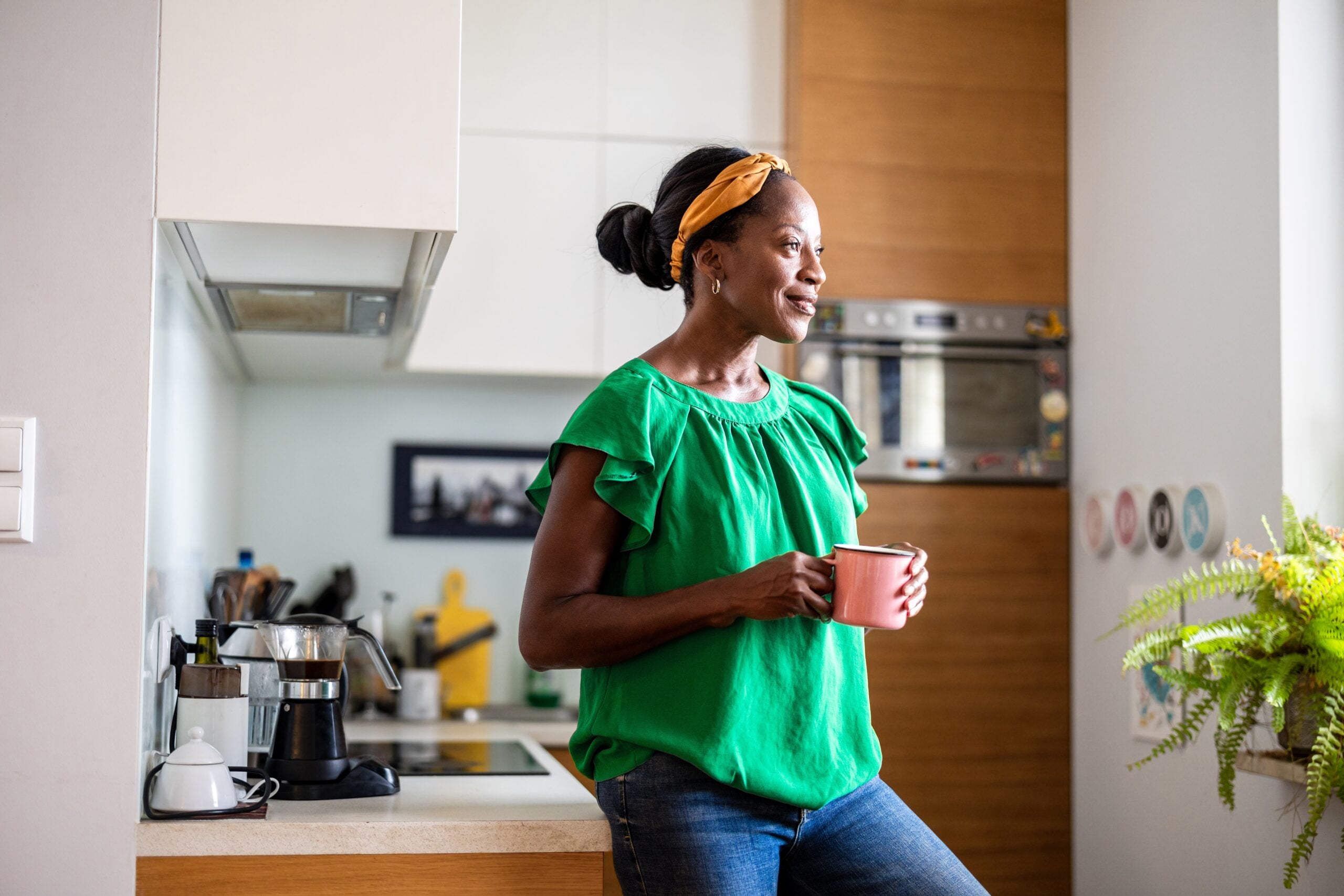 A middle aged woman in her kitchen having coffee.