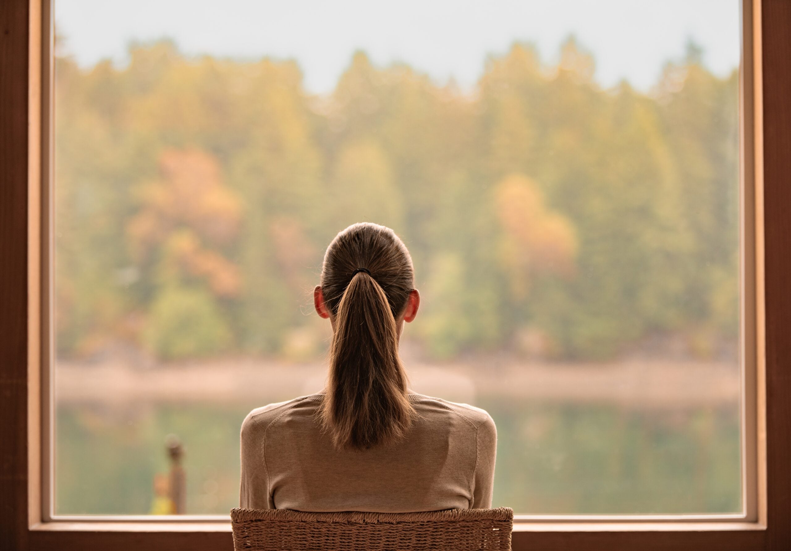 Lonely woman at home looking out her window.