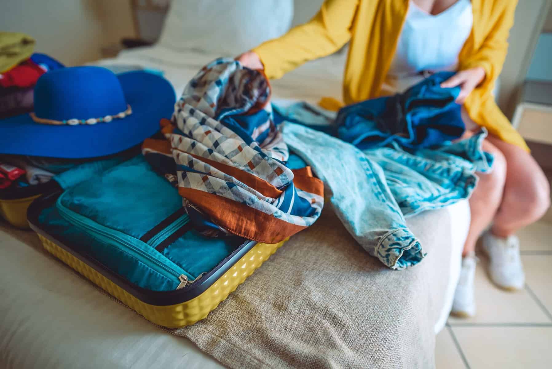 A woman overpacking clothes for her vacation.