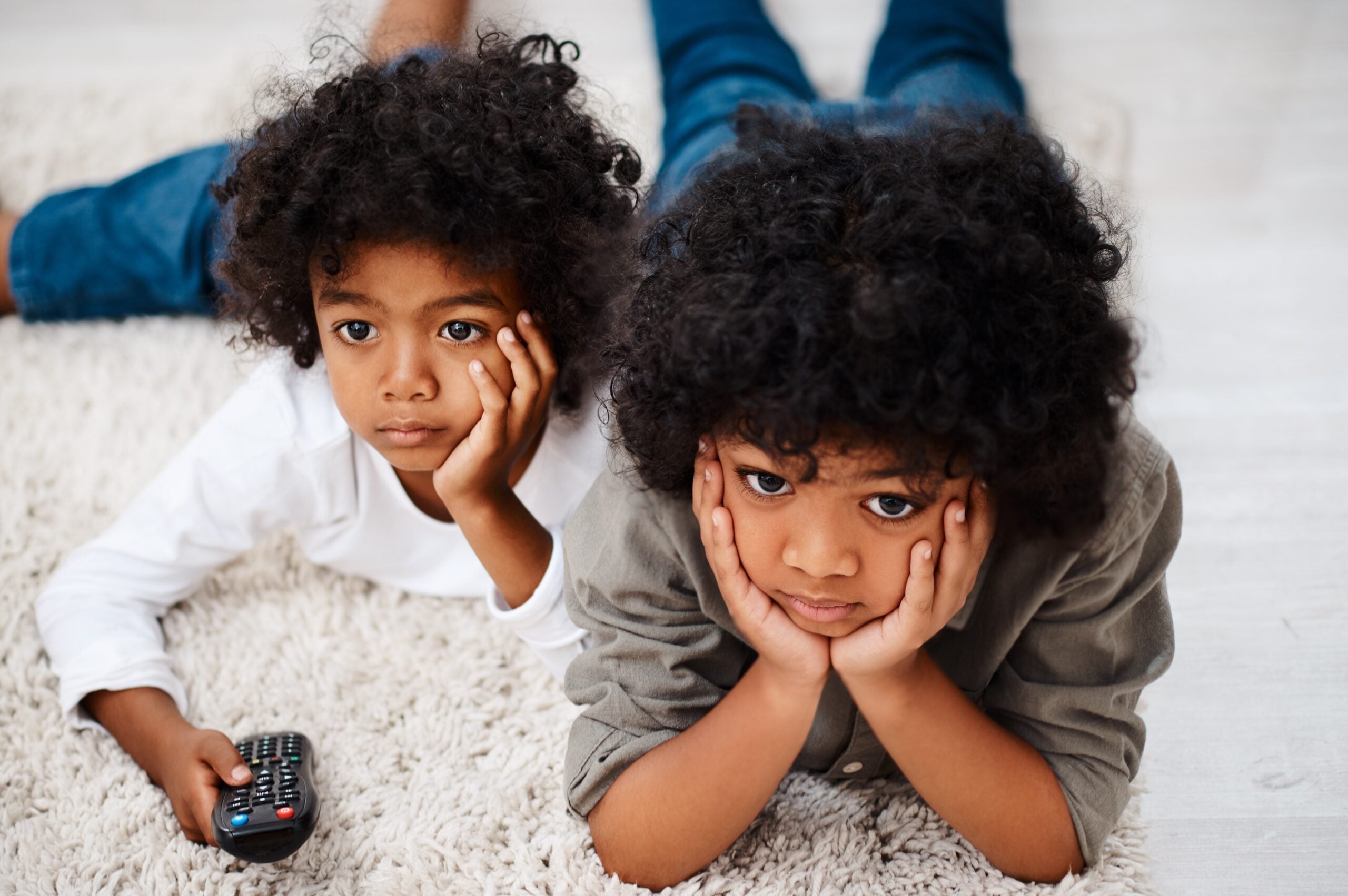 Two young siblings watching TV together.