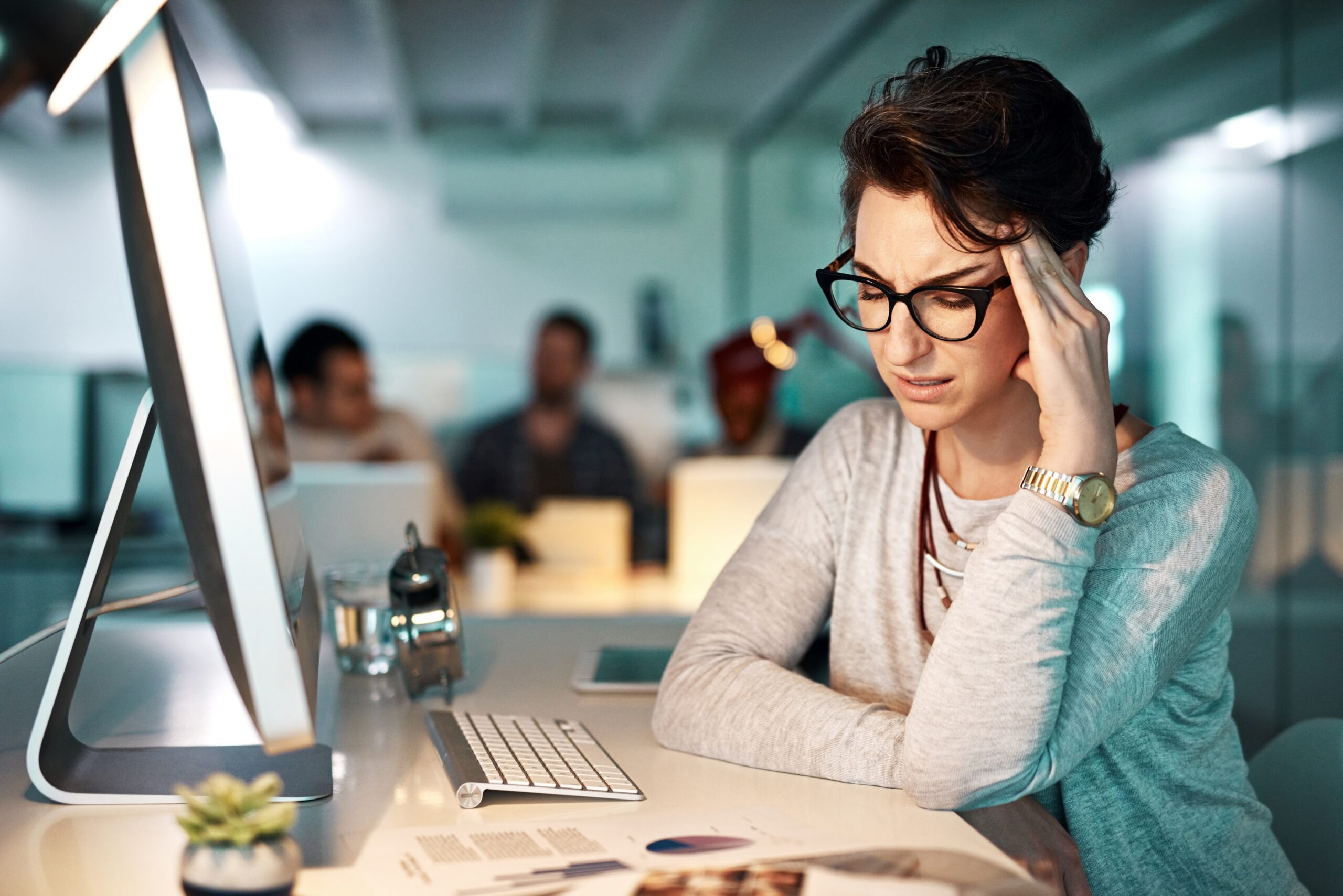 An unhappy woman feeling exhausted at her desk.