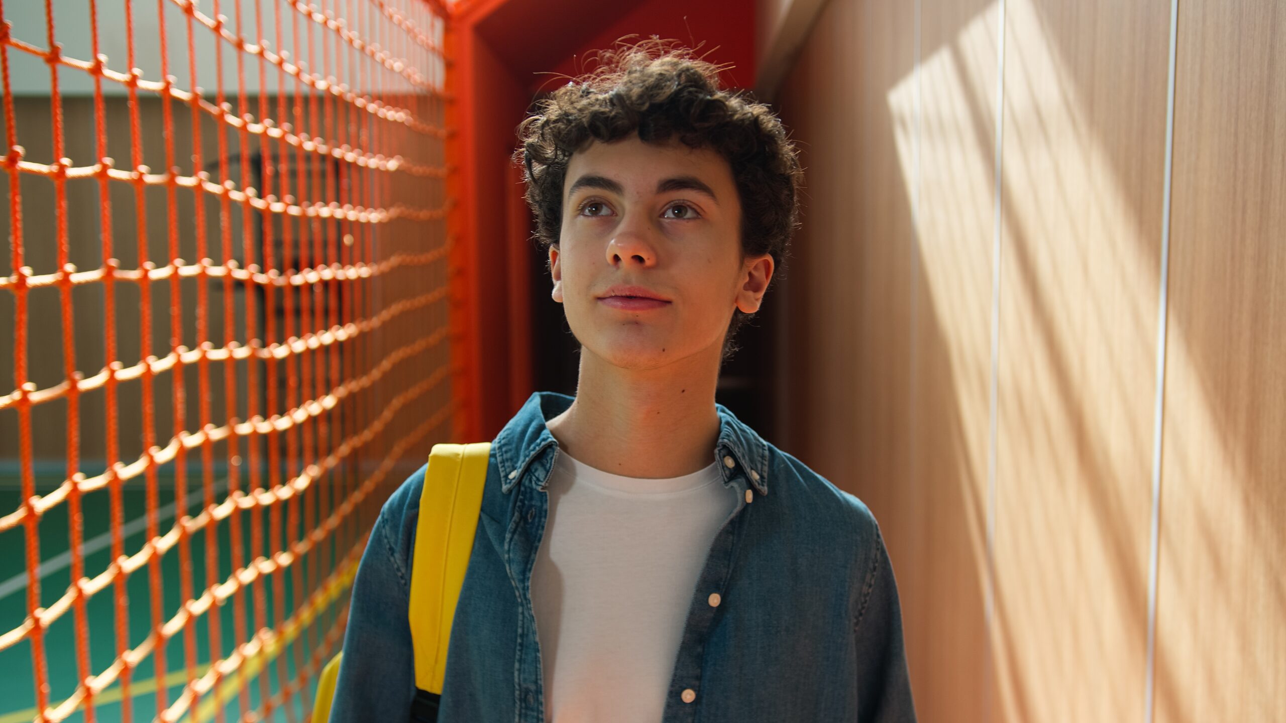 A teenage boy walking alone at the gym.