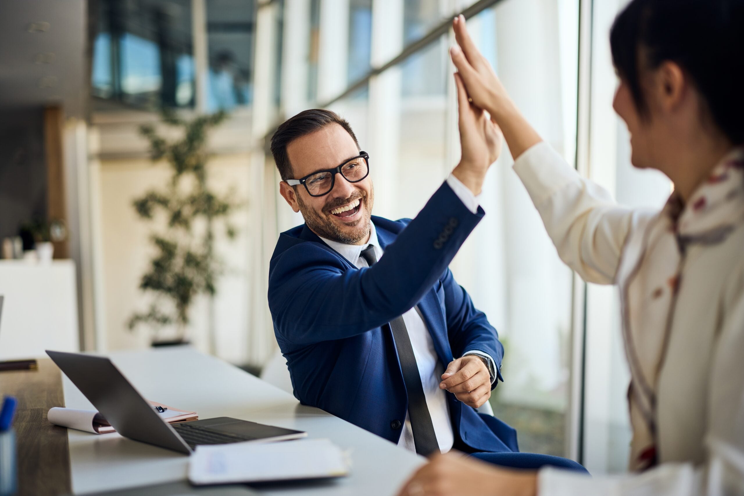 Two professionals high-fiving one another after a success.
