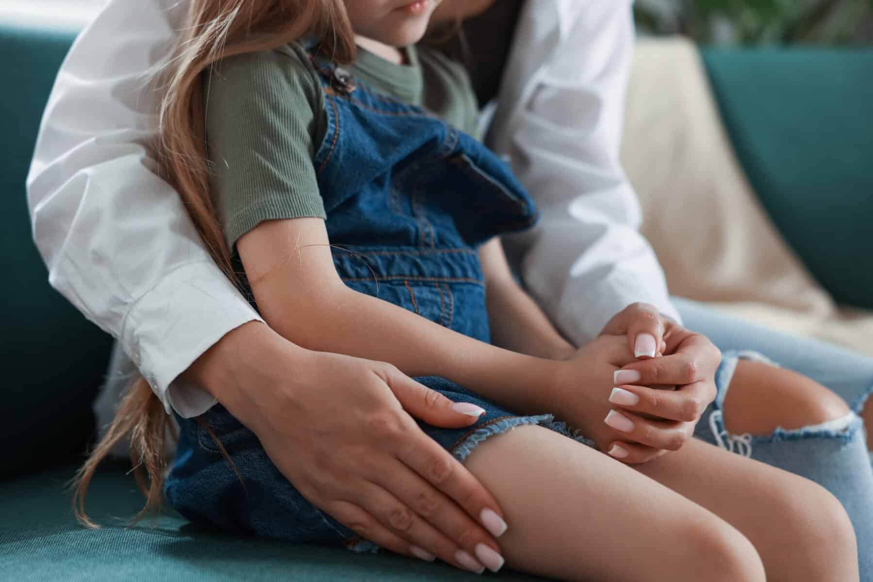 A mother with her young daughter holding hands after an apology at home.