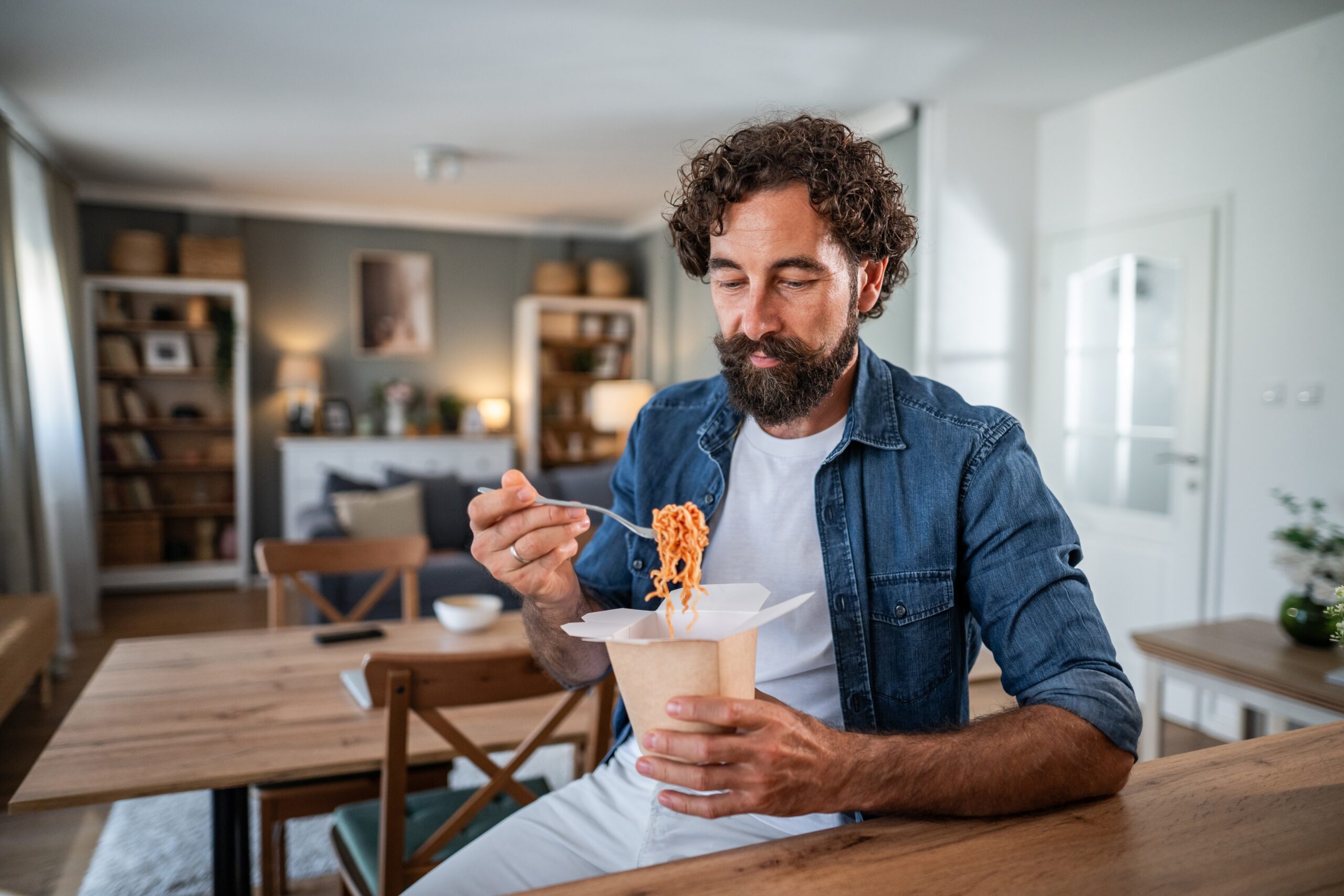 A single man eating take out food.