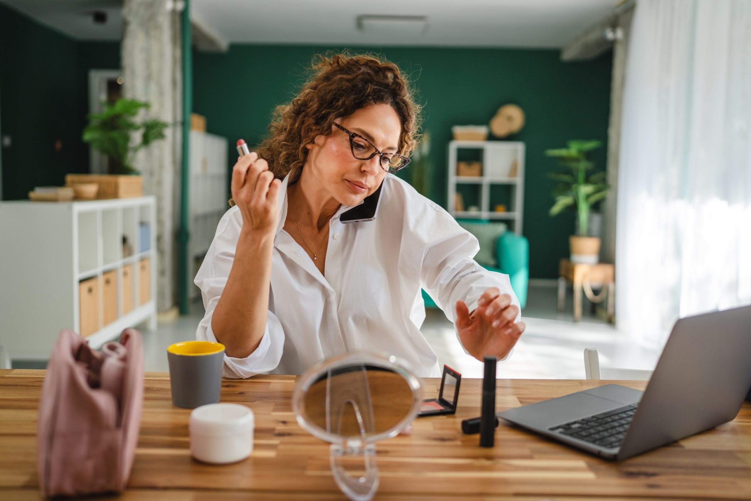 Woman putting on make-up while talking on the phone.