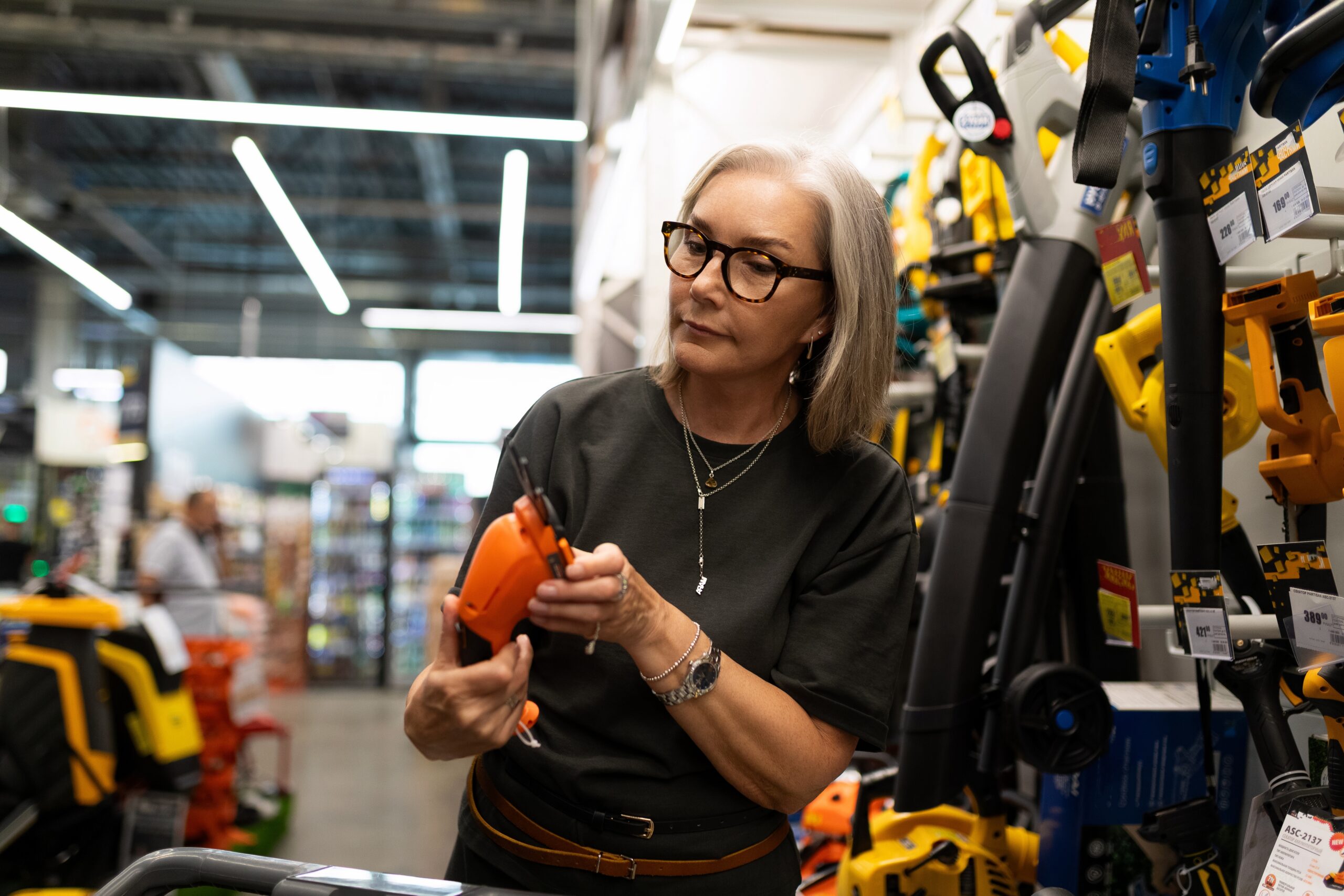 A woman looking at gardening tools in a home improvement store.