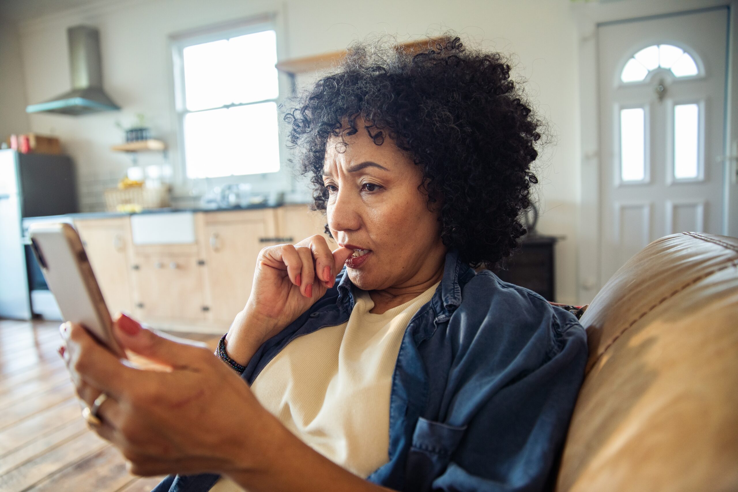 A middle aged woman texting on her phone at home.