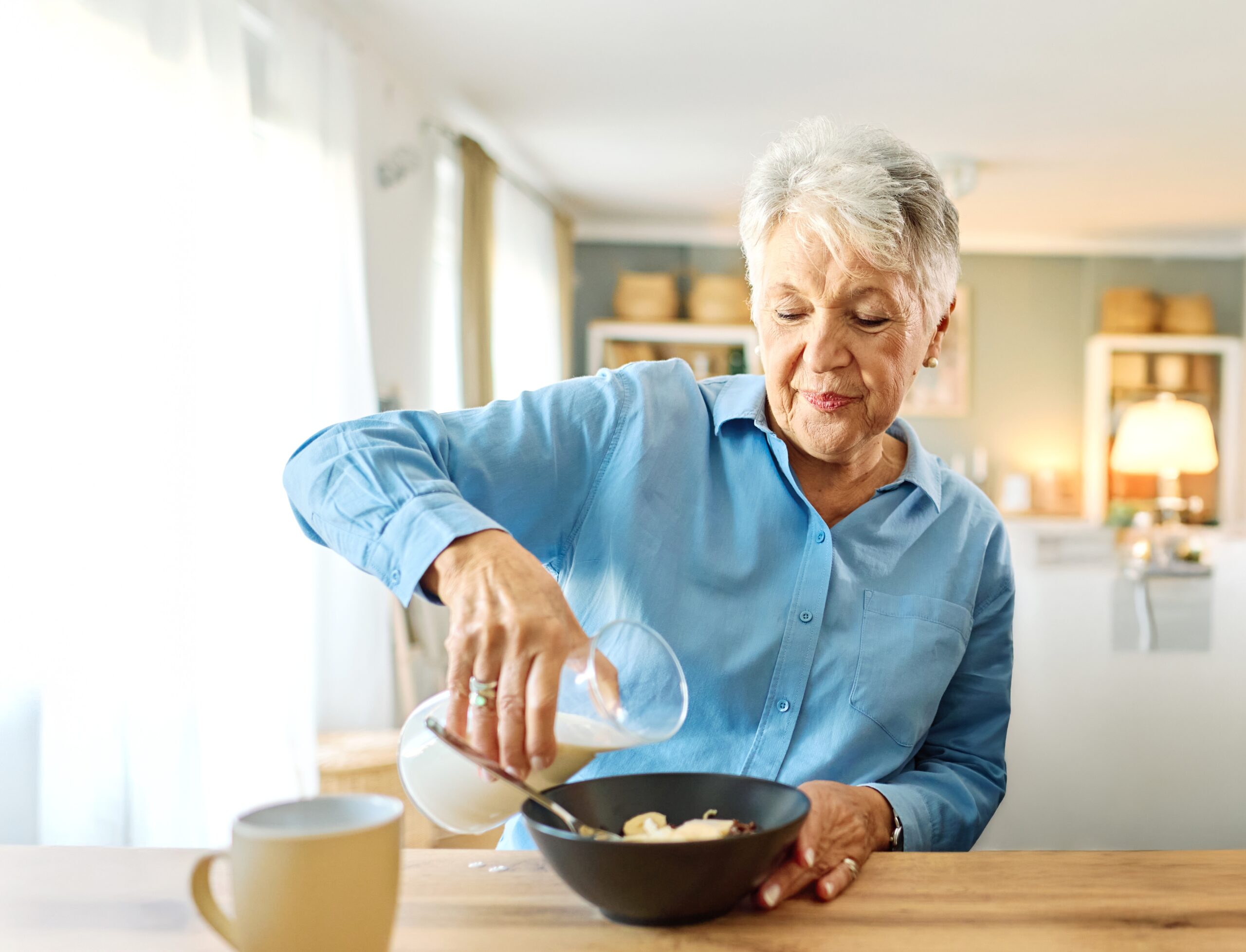 A content senior woman making breakfast at home.