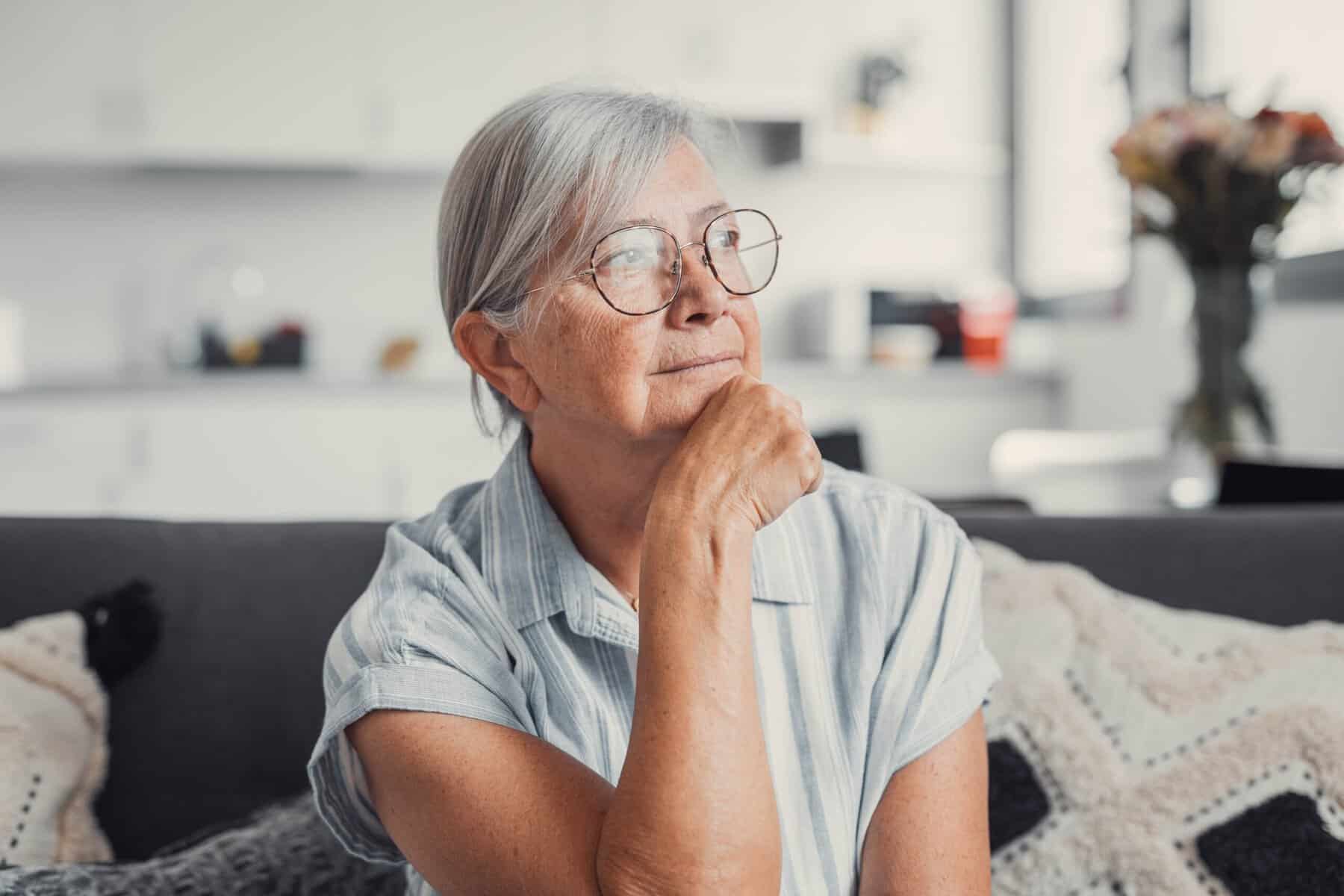 A senior woman sitting alone at home.
