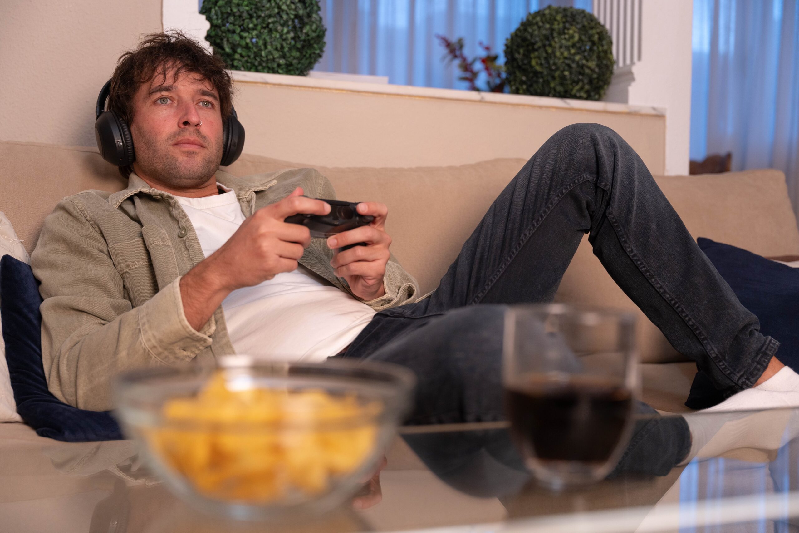 A man playing video games and eating chips.