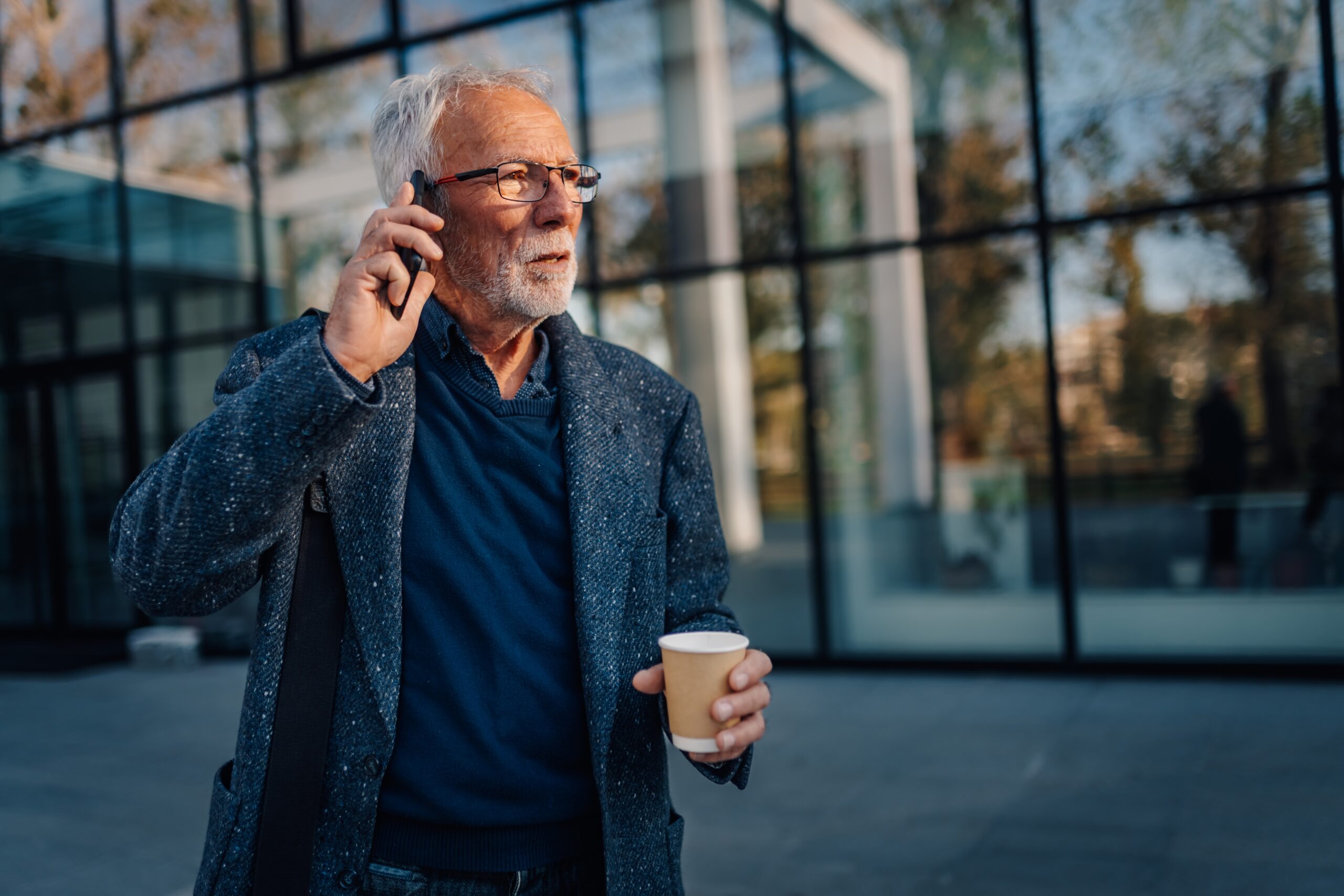 A senior man walking alone on his phone.