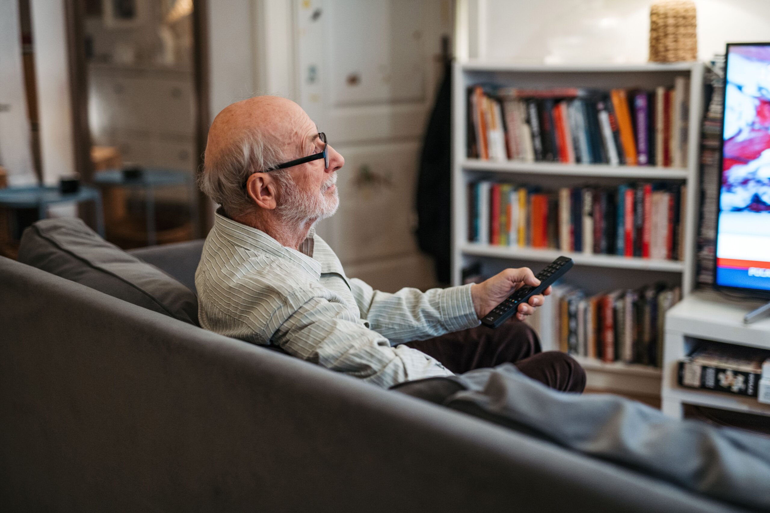 A senior man watching TV.