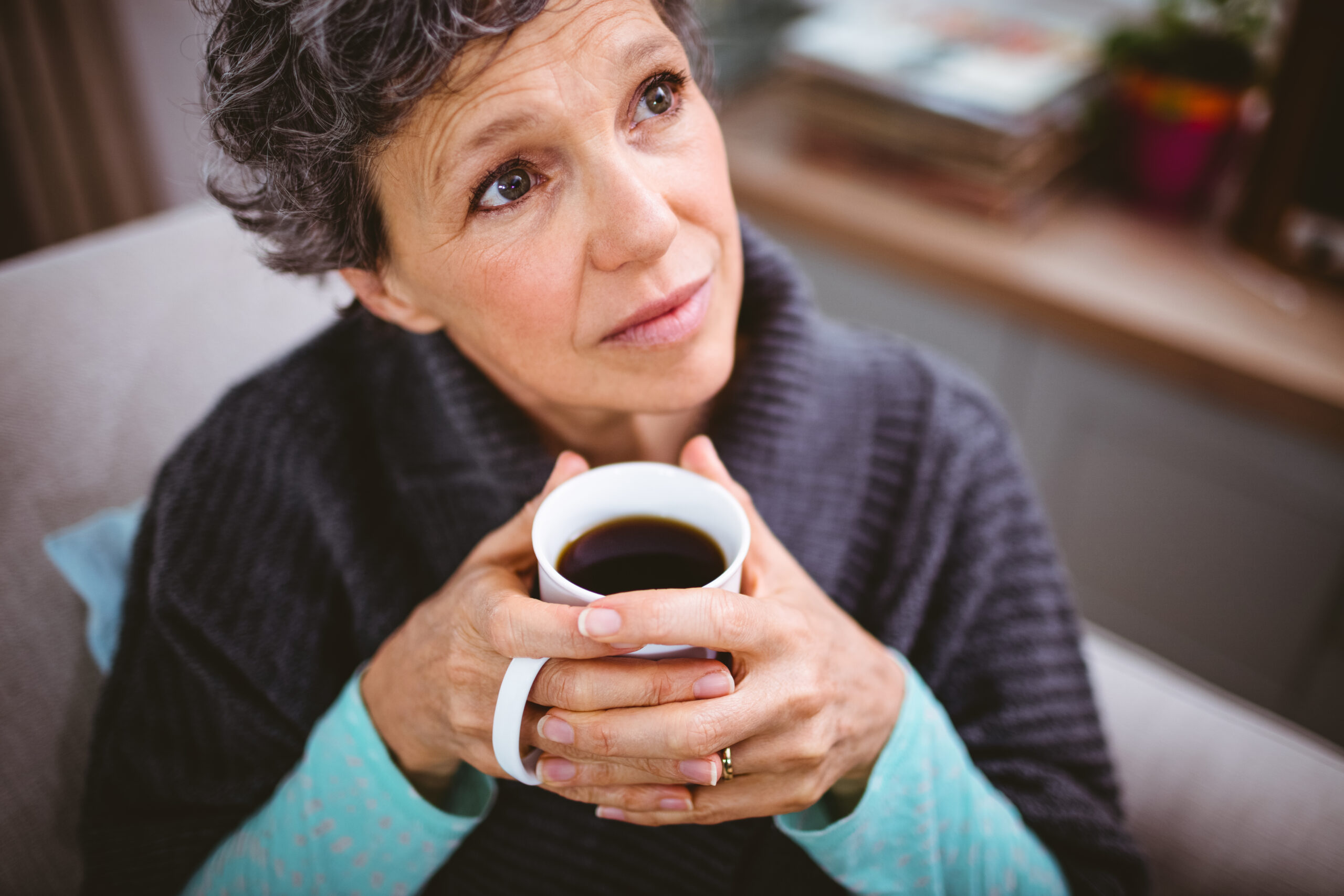 A thoughtful senior woman having coffee alone.