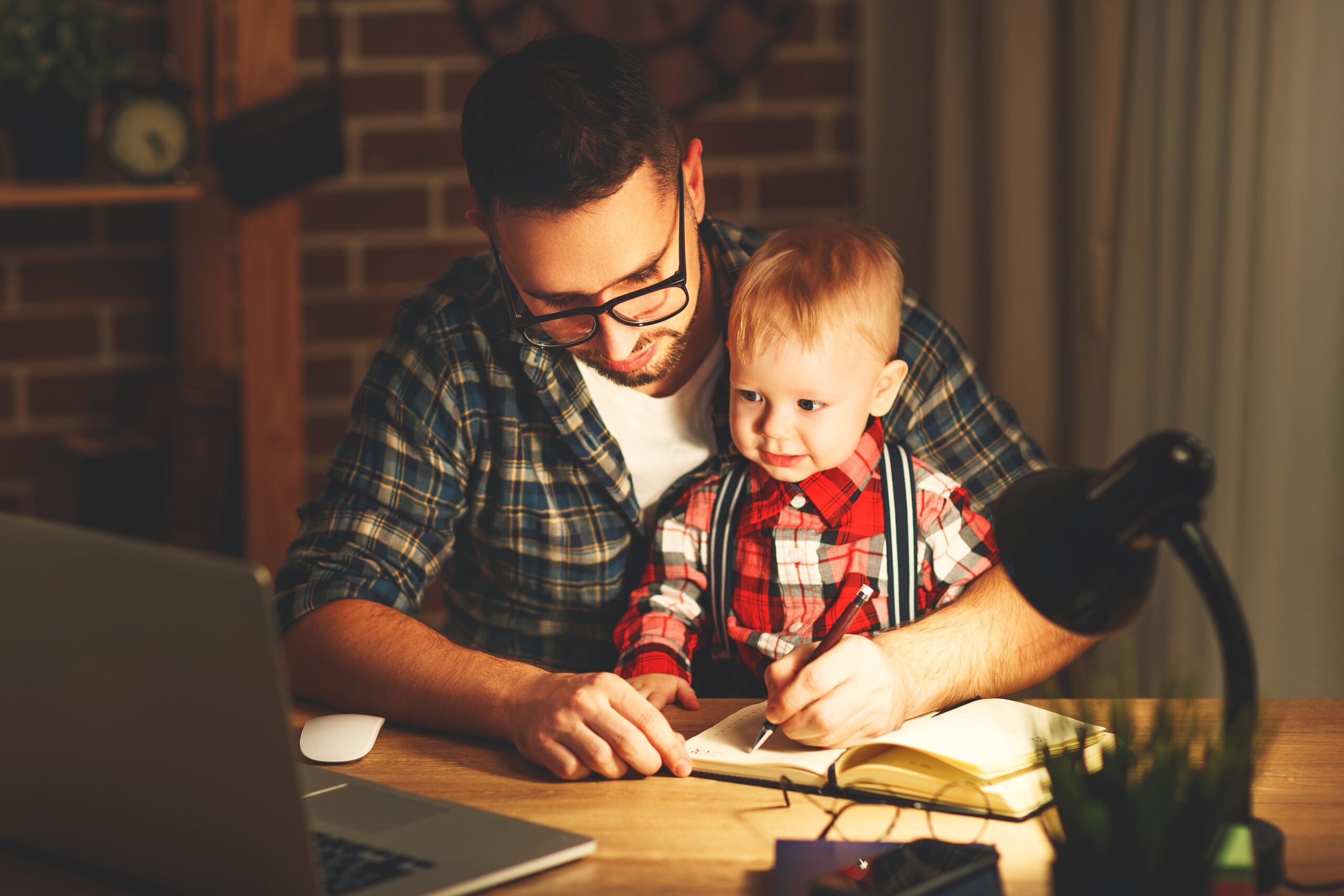 A busy working father with his son on his lap.