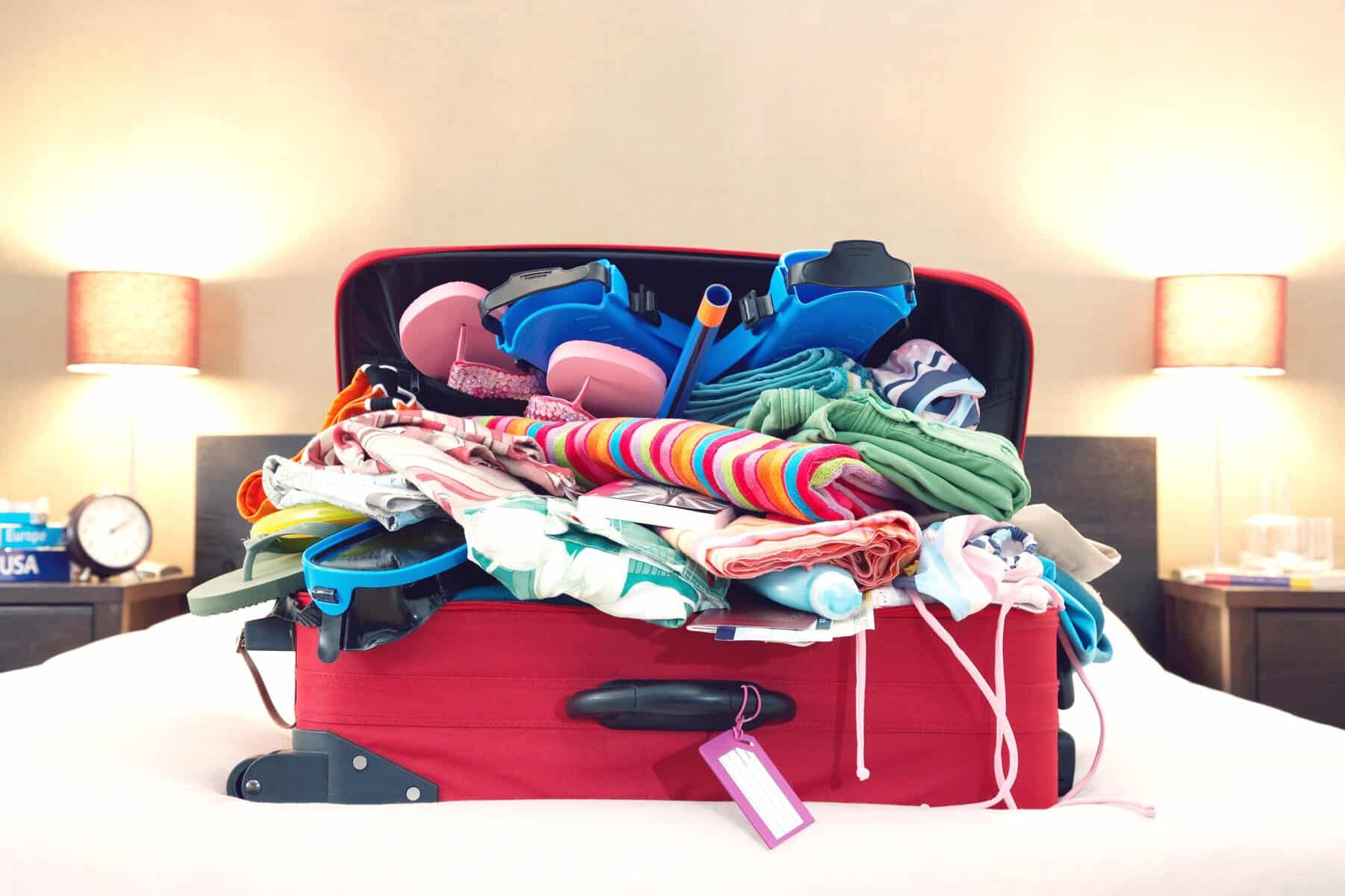 An overpacked suitcase on a bed.