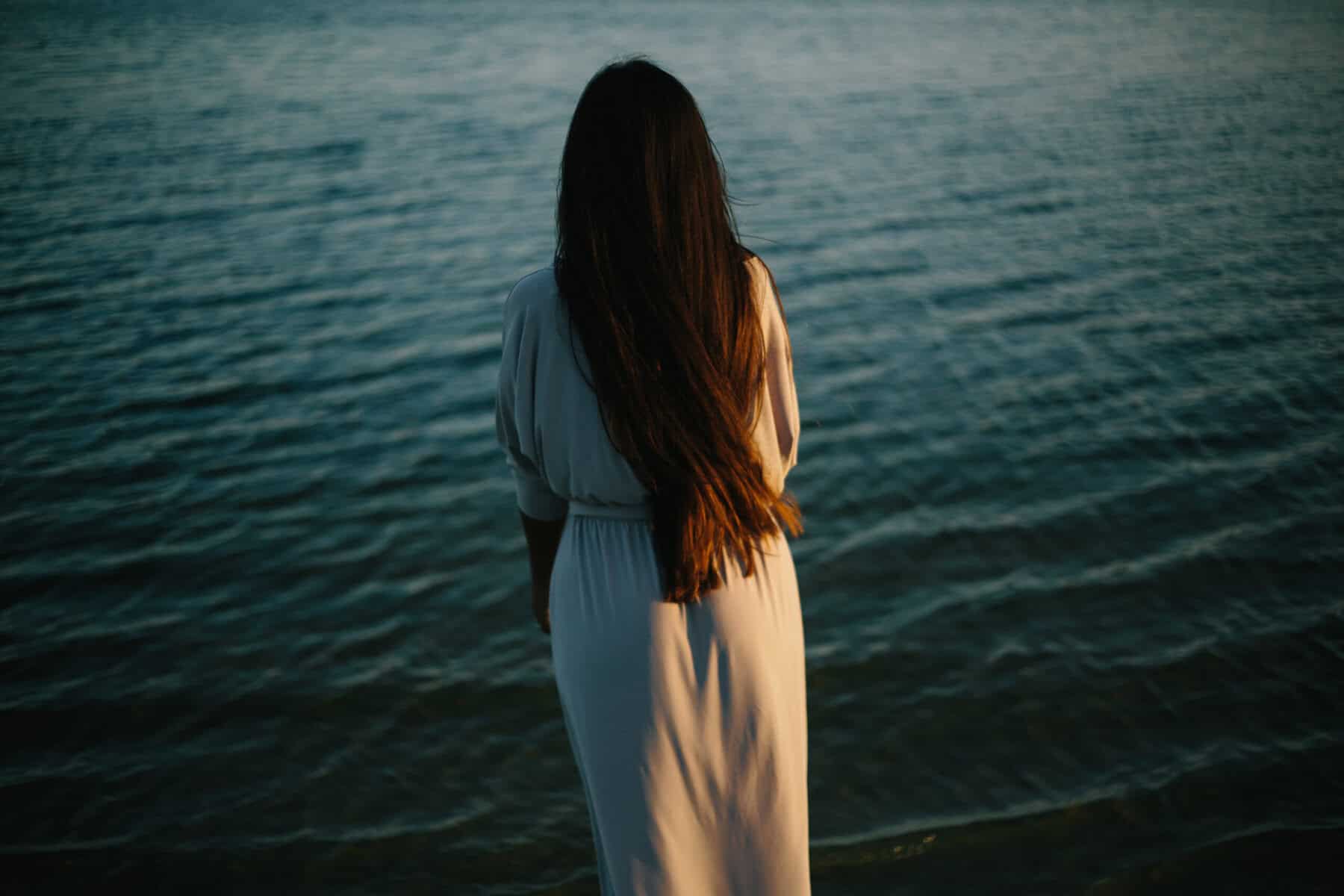 Woman standing on beach looking at horizon alone.