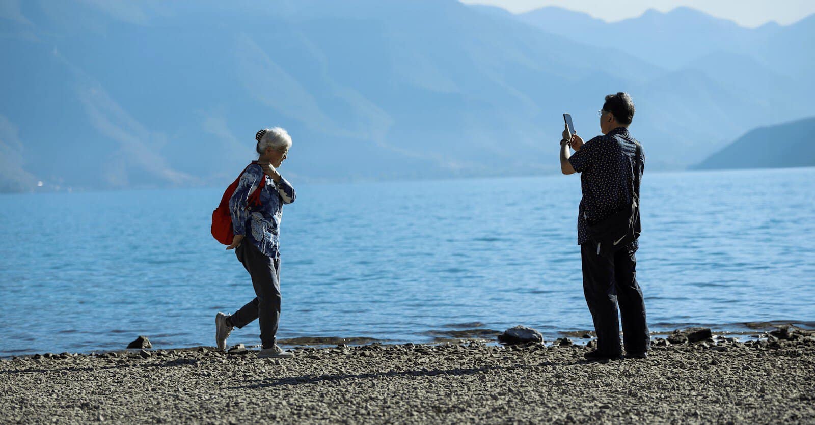 Senior couple by a serene lake in China, capturing memories on a sunny day.