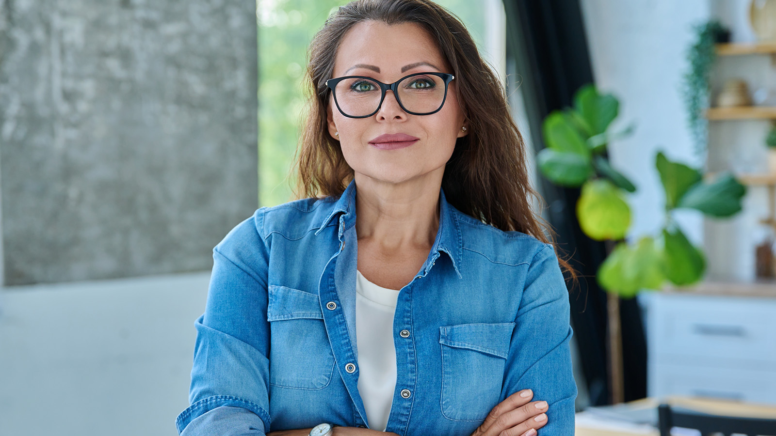 Confident woman in her 40s, wearing glasses, smiling confidently