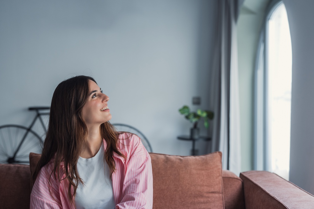A smiling young woman relaxes on a couch at home