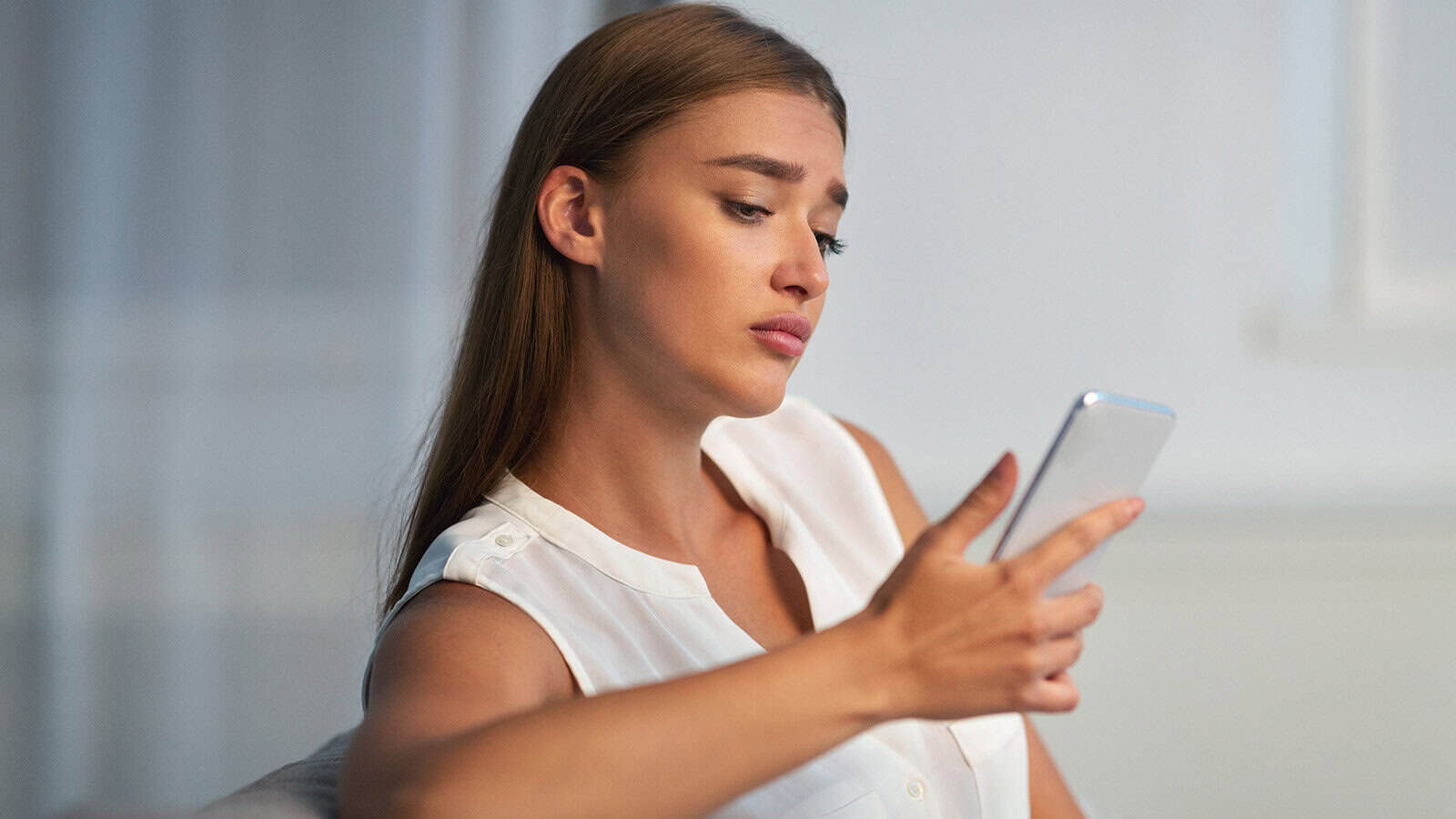 Woman sad, waiting by her phone for a guy to text.