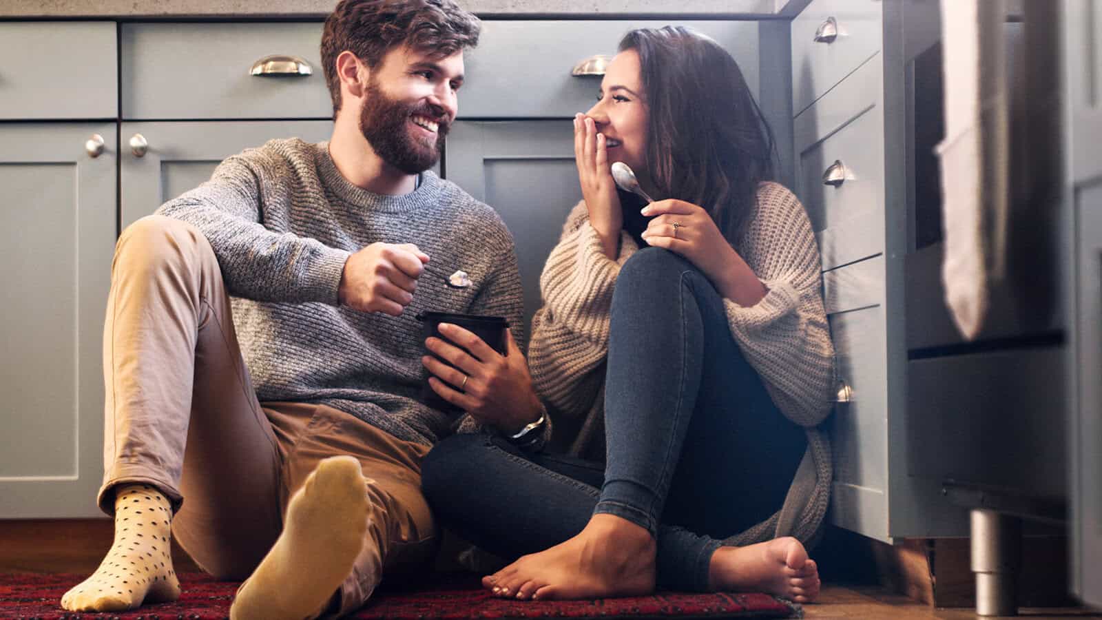 Husband and wife enjoying each other's company in the kitchen, laughing.