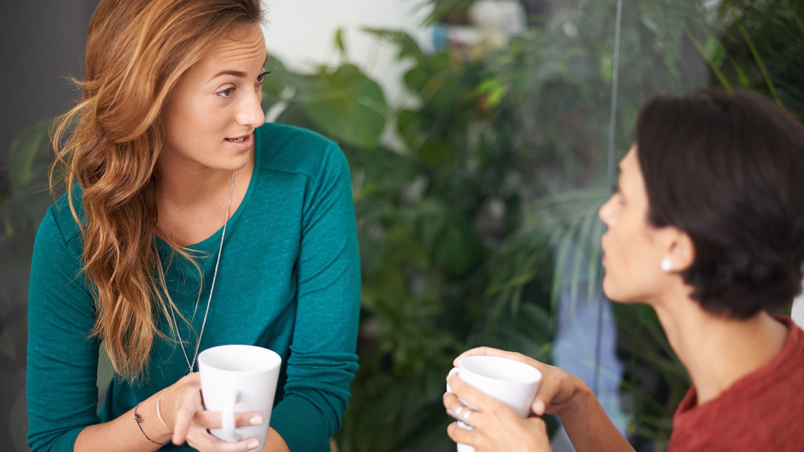 Is that so. Shot of two female professionals having a discussion over coffee in an informal office setting.