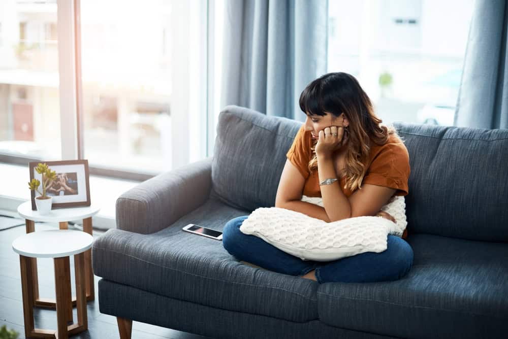 Woman bored sitting on a couch reaching for her phone
