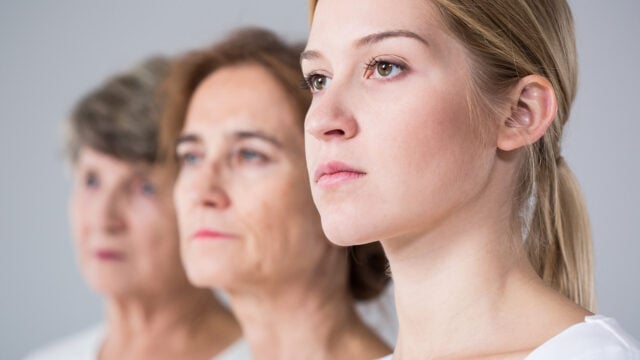 Three women of different ages stand side by side, facing forward. The youngest woman, representing Gen Z, is in sharp focus in the foreground, while the older millennial women behind her are blurred. All have serious expressions.