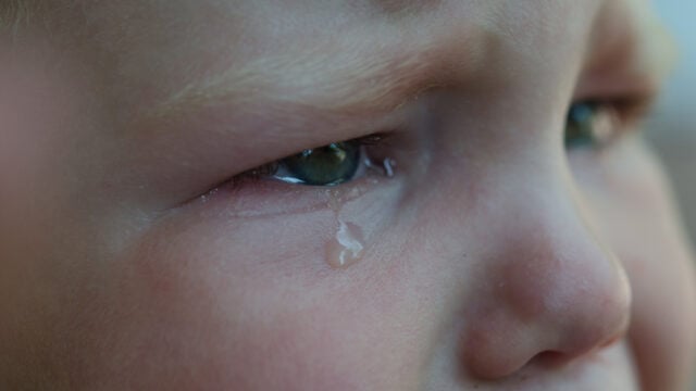Close-up of a child’s face, showing a teardrop rolling down from their eye, with an expression of sadness or distress—capturing the emotional impact of discipline often used by Boomer-era parents as punishment.