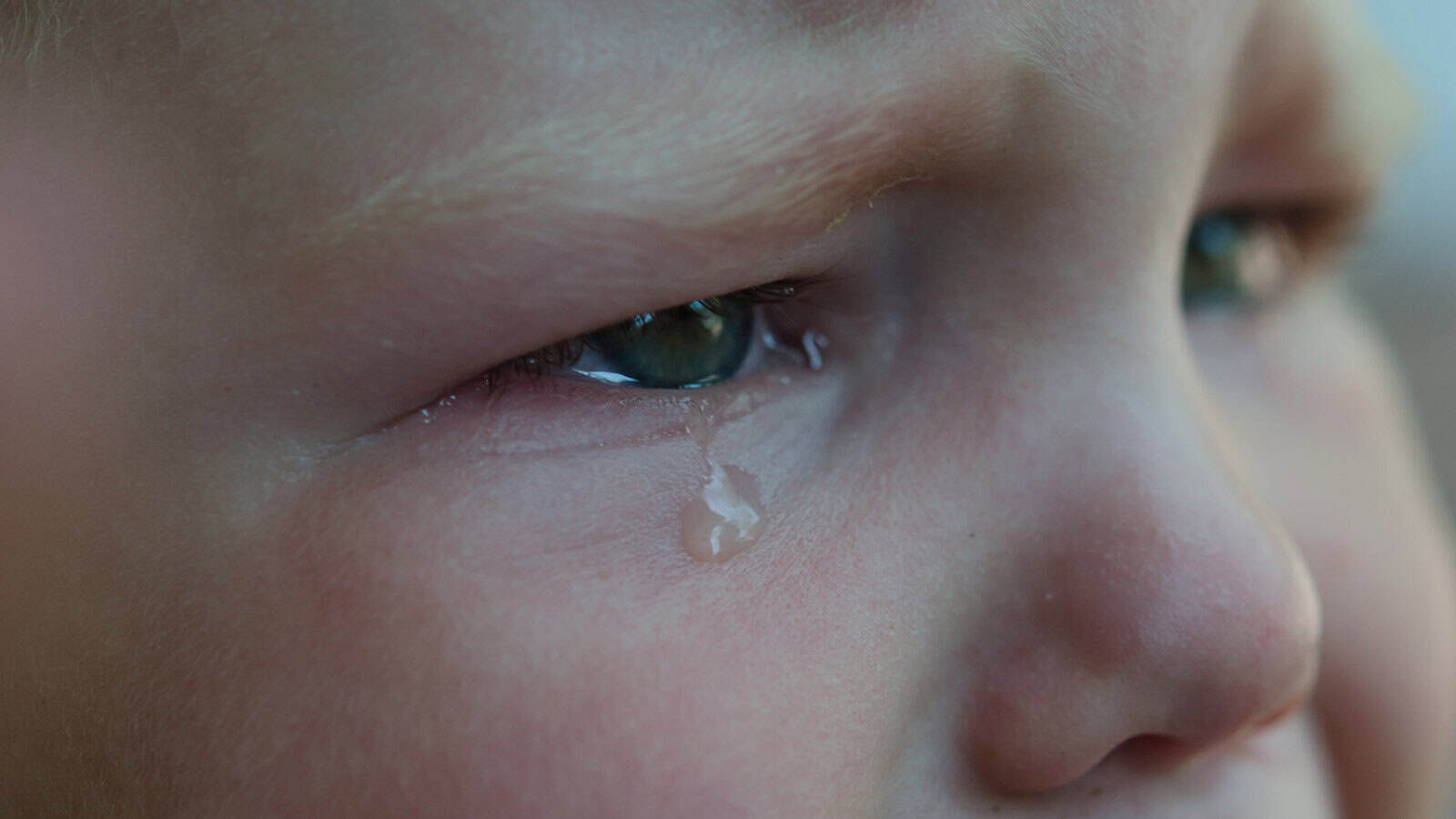 Close-up of a child’s face, showing a teardrop rolling down from their eye, with an expression of sadness or distress—capturing the emotional impact of discipline often used by Boomer-era parents as punishment.