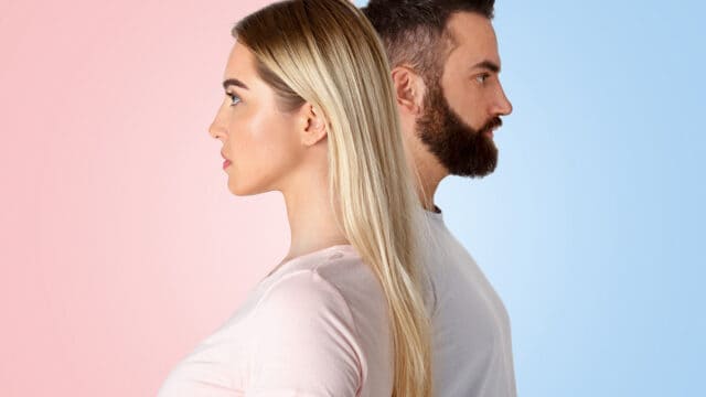 A woman and a man stand back to back, facing opposite directions. The background is split vertically, with pink on the left and blue on the right.