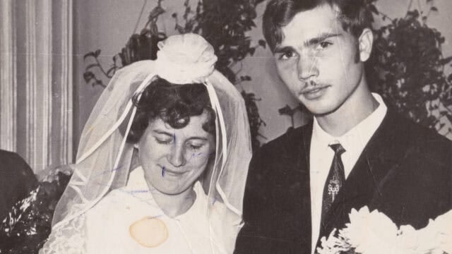 A vintage black-and-white photo of a bride in a veil and a groom in a suit, both standing close together and holding flowers, with visible age marks and creases on the image—a timeless snapshot capturing the essence of a good marriage that still inspires Millennials and Gen Z today.