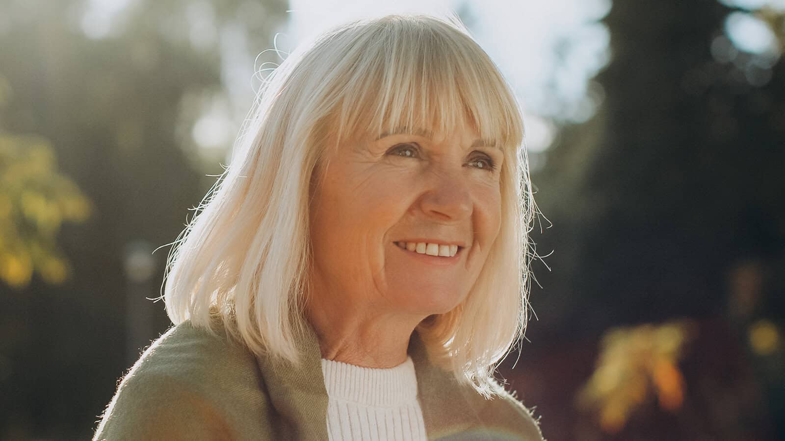 A smiling older woman with blonde hair looking away from the camera.