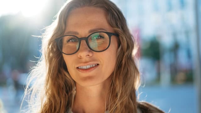 Close-up portrait of a smiling woman wearing black-rimmed glasses.