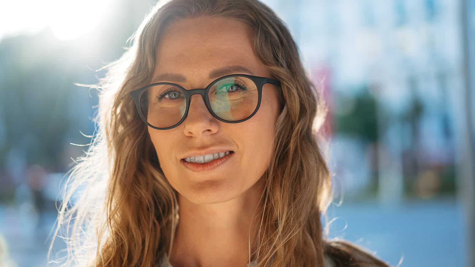 Close-up portrait of a smiling woman wearing black-rimmed glasses.