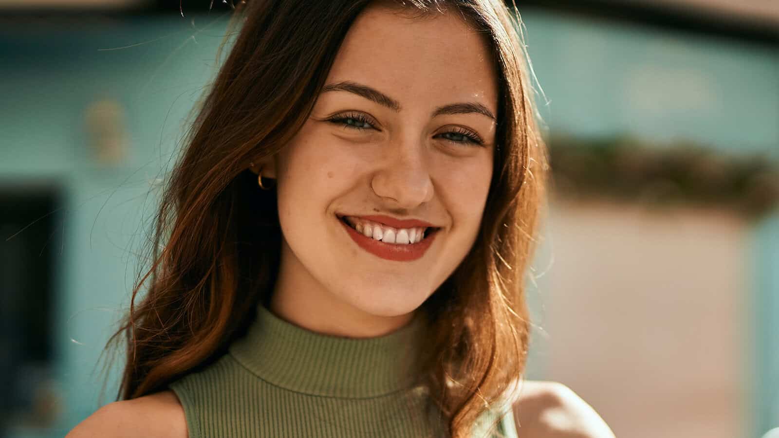 A young woman with long brown hair smiling at the camera.