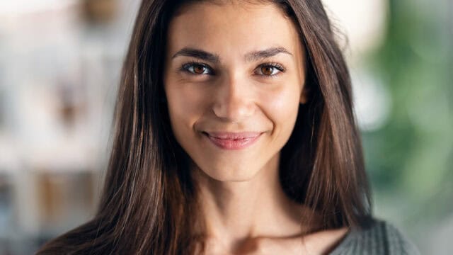 Close-up portrait of a smiling woman with long brown hair.