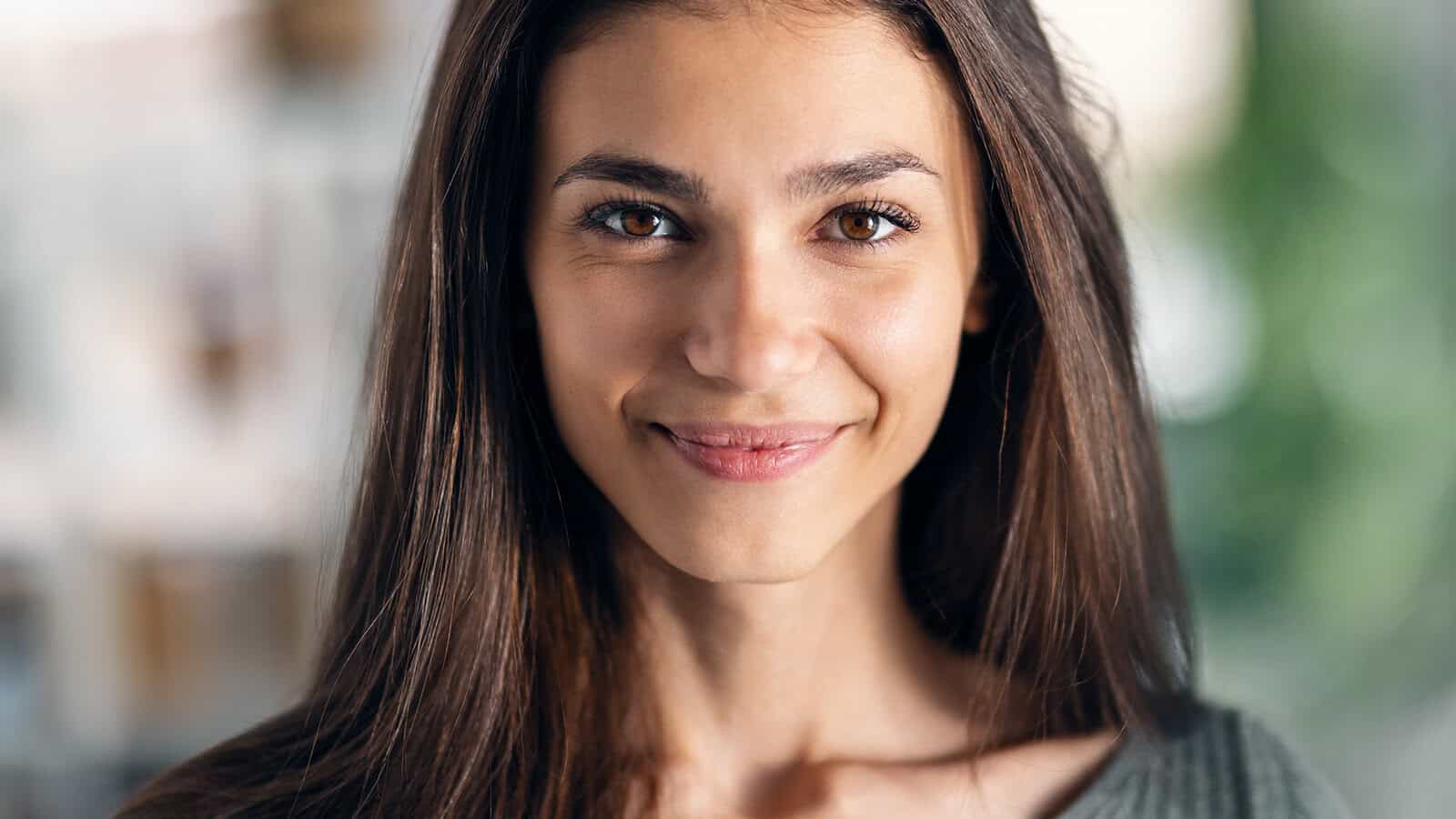Close-up portrait of a smiling woman with long brown hair.