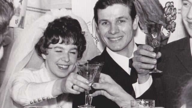 A smiling bride and groom toast with champagne glasses at their wedding.