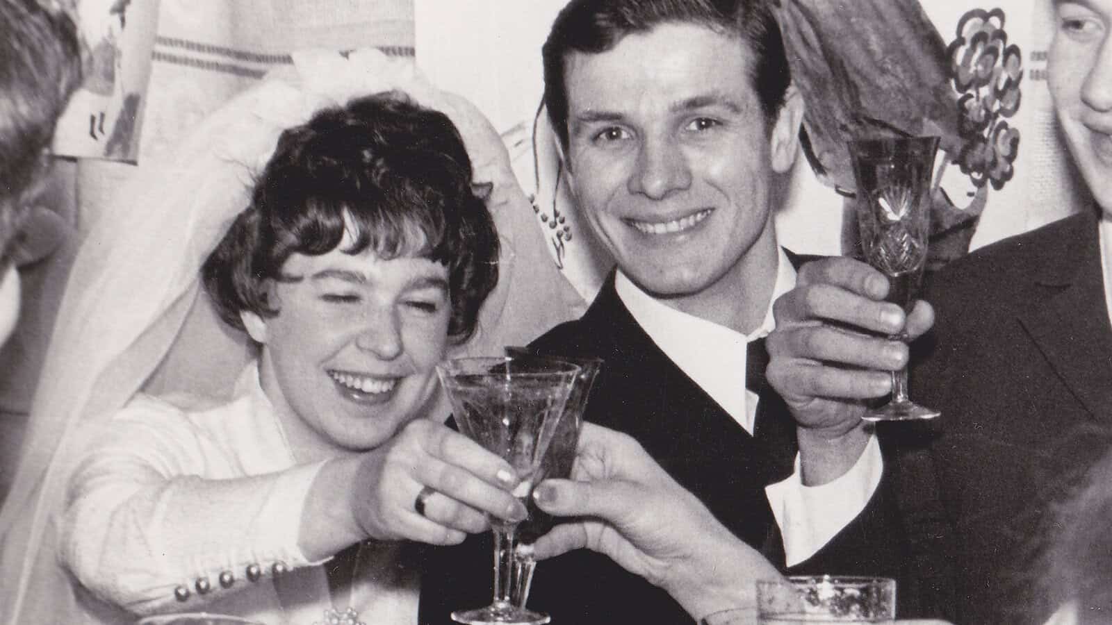 A smiling bride and groom toast with champagne glasses at their wedding.