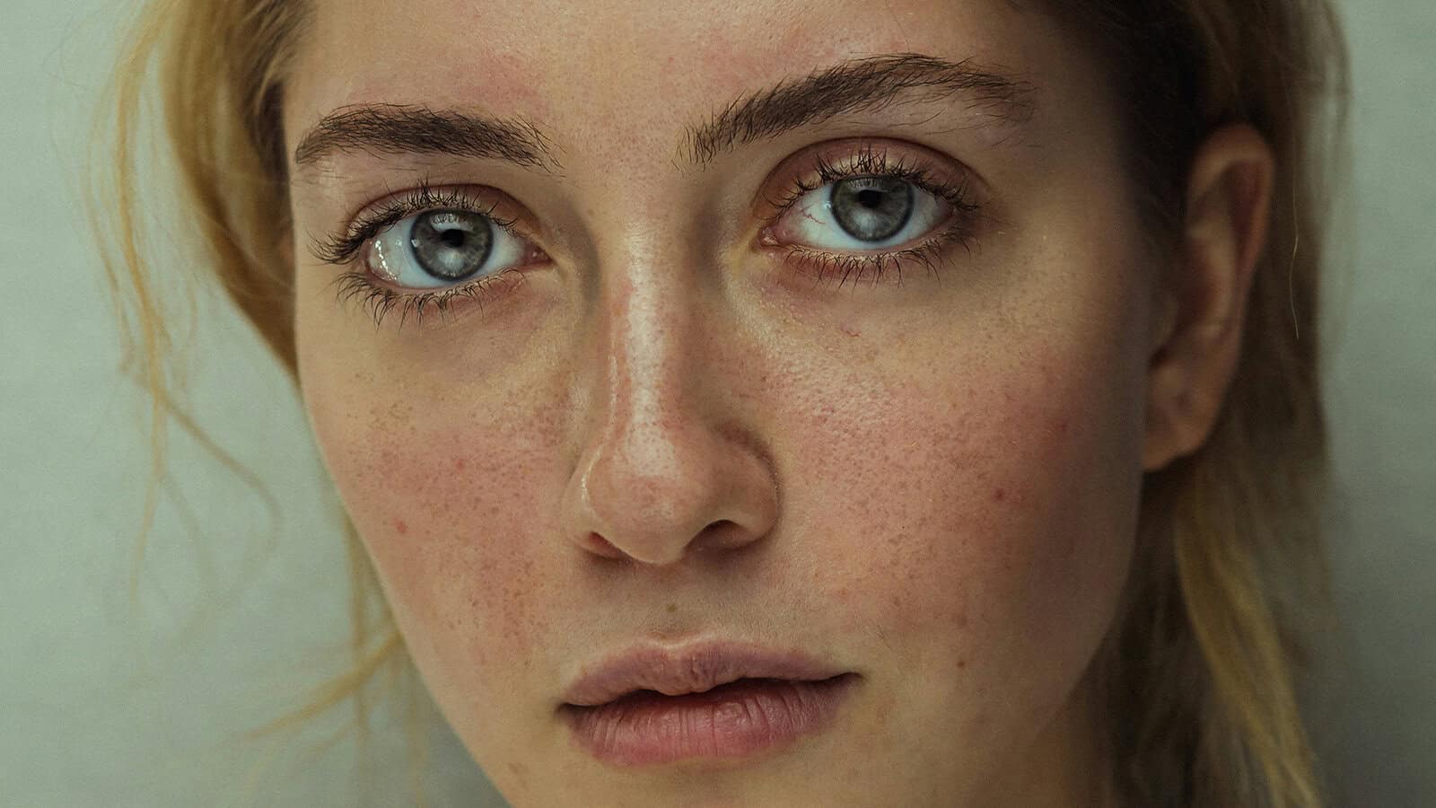 Close-up portrait of a woman with grey eyes and visible skin texture.