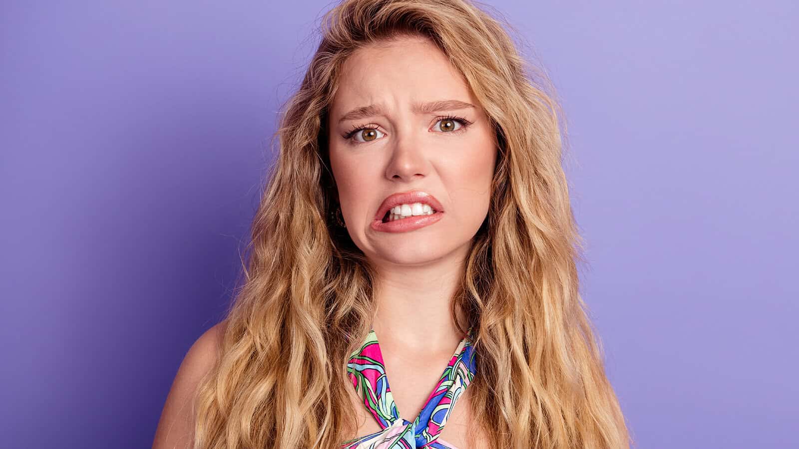 A young woman with long blonde hair looks at the camera with a grimacing, skeptical expression.